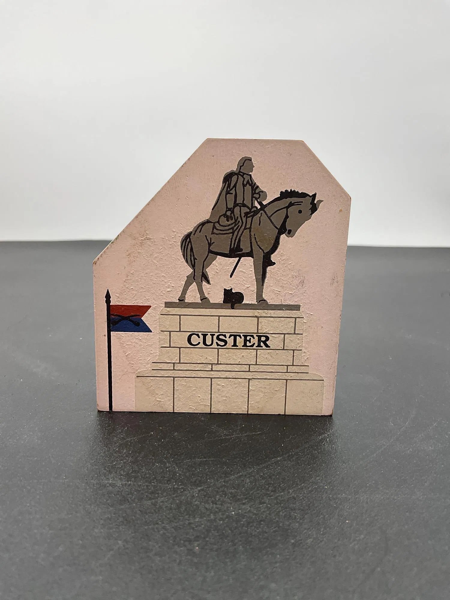 General George Armstrong Custer Commemorative Keepsake: This is a commemorative stone keepsake honoring General George Armstrong Custer (1839-1876). The front features an illustration of Custer on horseback atop a monument, while the back provides