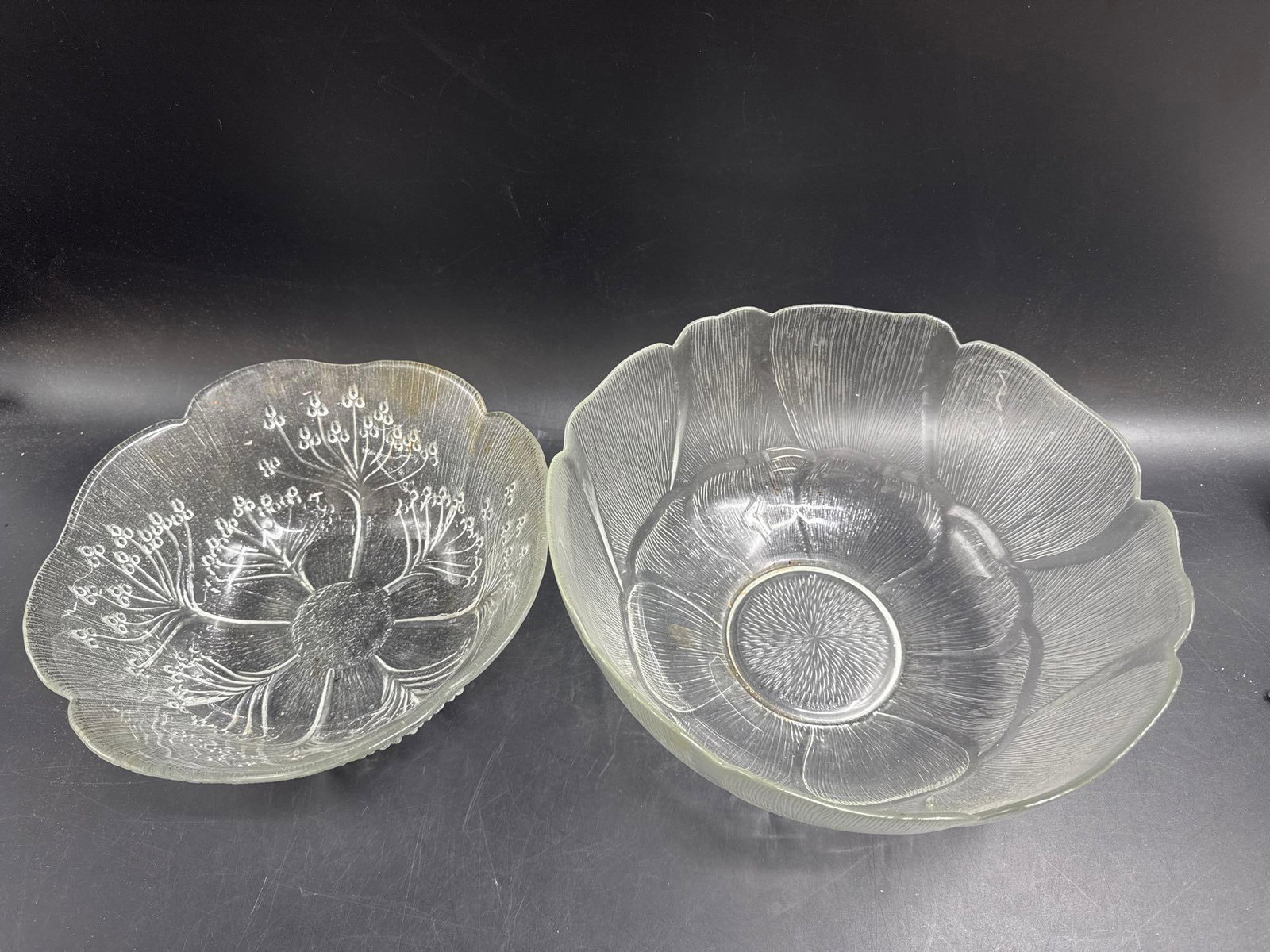 Pair of Vintage Pressed Glass Floral Bowls:  Two clear pressed glass bowls, each molded in the shape of a flower. One features a detailed blossom with etched petal and stamen design, while the other has a broader petal pattern radiating fr