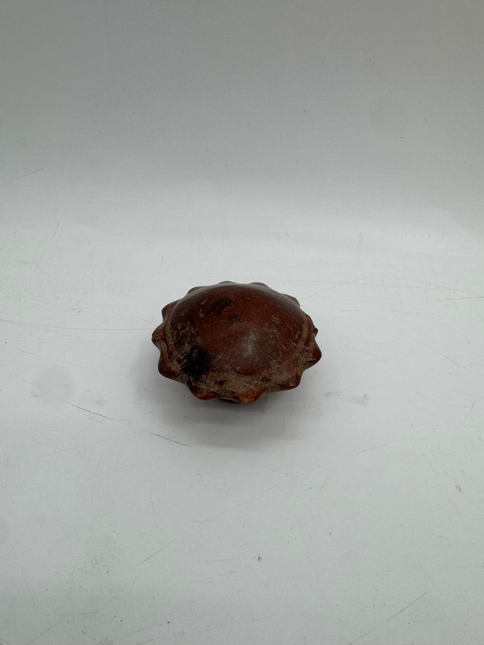 Pre-Colombian Small Decorative Ceramic Object: A small, possibly hand-crafted, decorative ceramic object. It features a textured surface and a hollow interior. Approximately 3 inches in diameter.