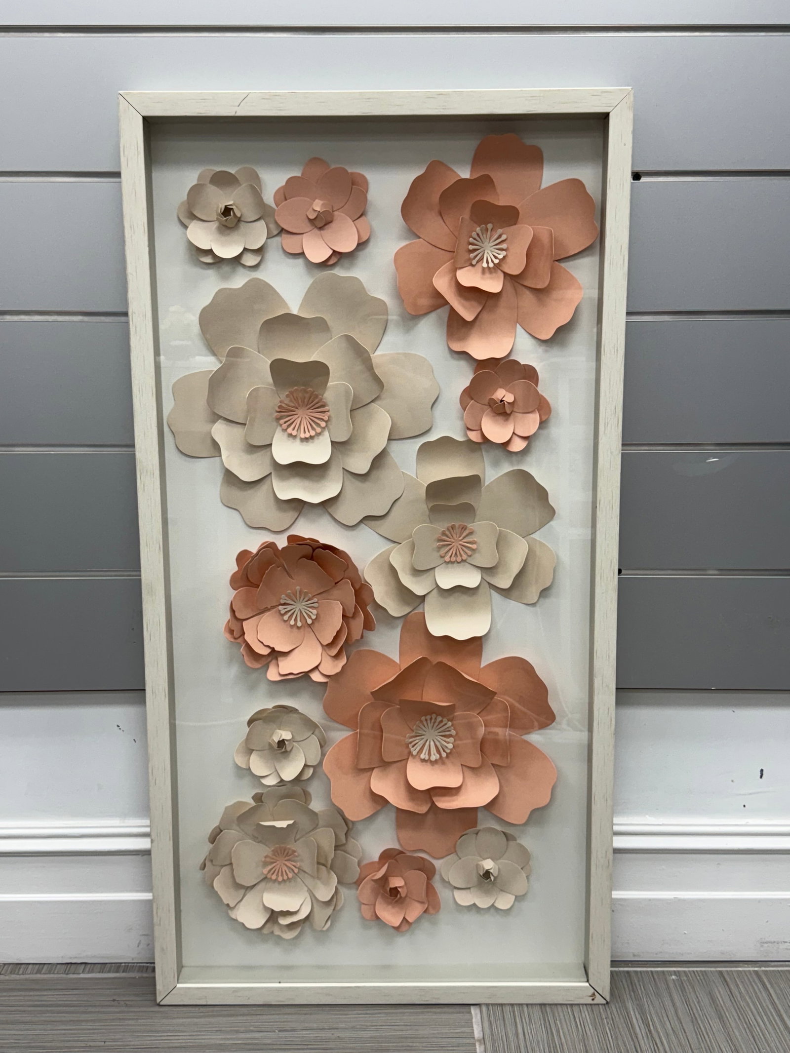 Shadow Box with 3D Paper Flowers: Decorative shadow box featuring layered three-dimensional paper flowers in soft beige and peach tones, arranged against a white background within a wooden frame. Dimensions: 41.5 x 21.5 inches.