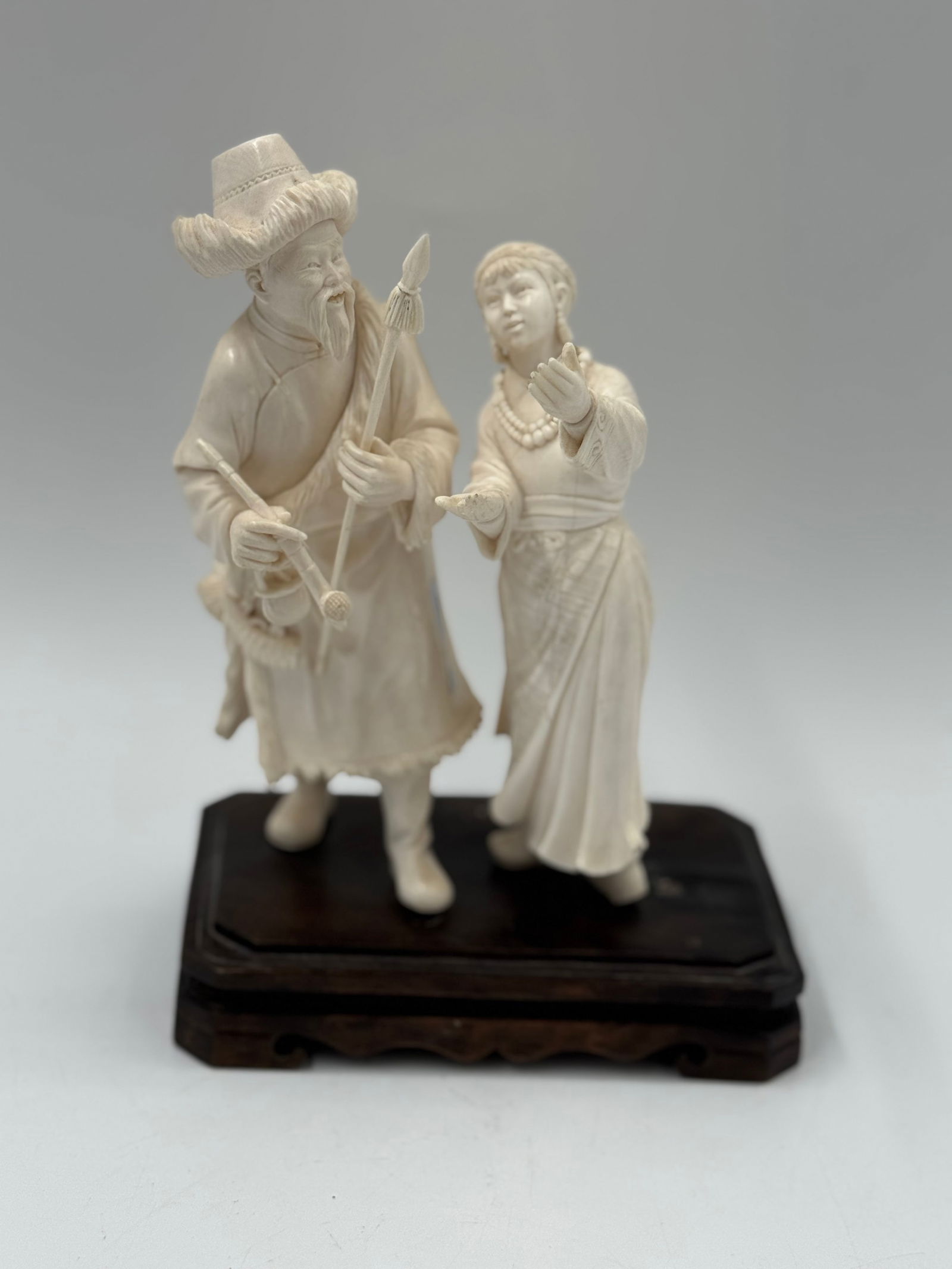 Vintage Carved Figurine of Man and Woman on Stand: Vintage carved figurine depicting a man and woman in traditional clothing, mounted on a dark wooden stand. The figurine is intricately detailed.6x4x8.5in