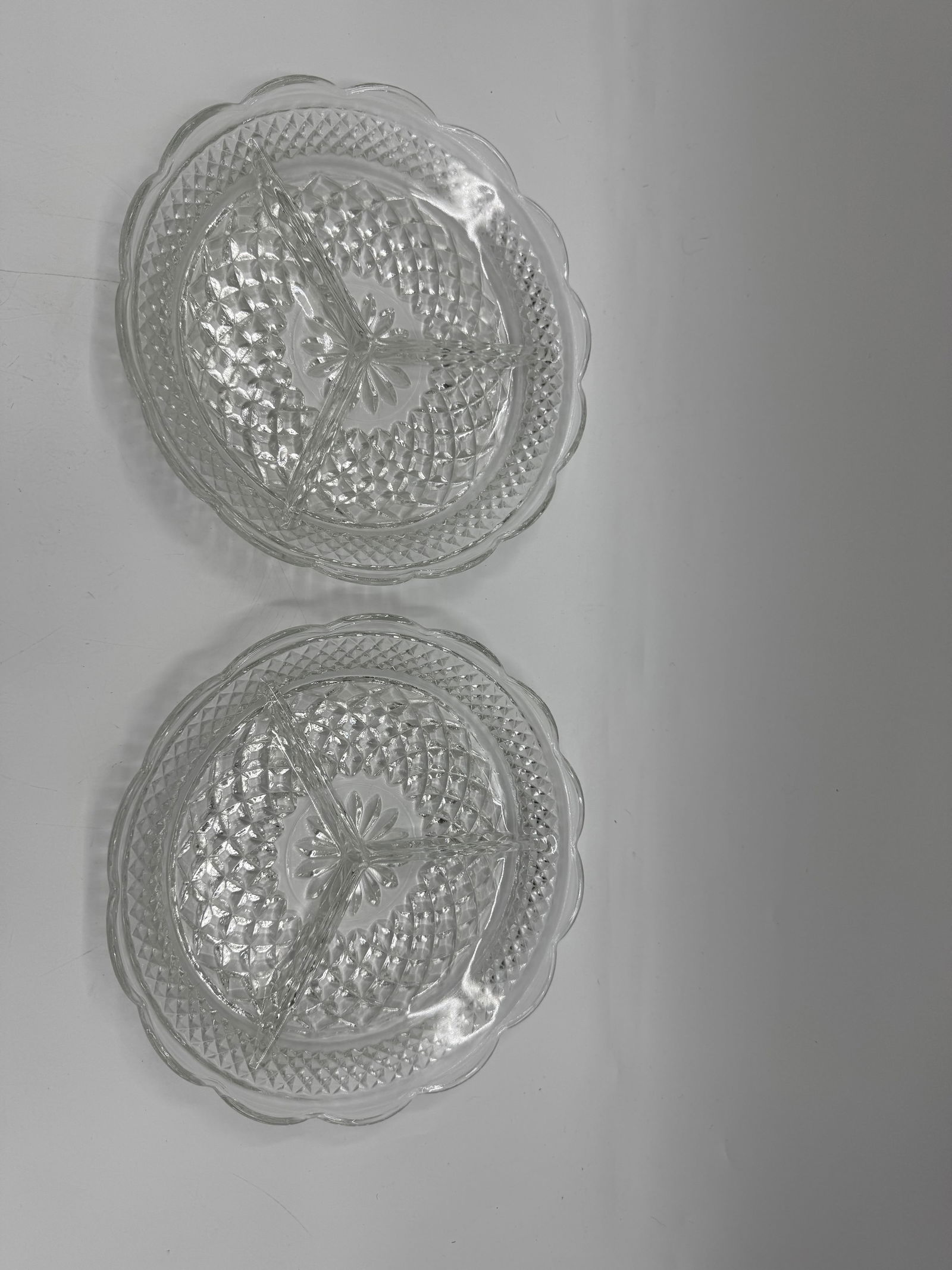 Pair of Vintage Clear Glass Divided Serving Dishes: Pair of clear glass serving dishes, each divided into three sections. Features a scalloped edge and intricate diamond-cut pattern. Each dish measures approximately 9 inches in diameter. Ideal for