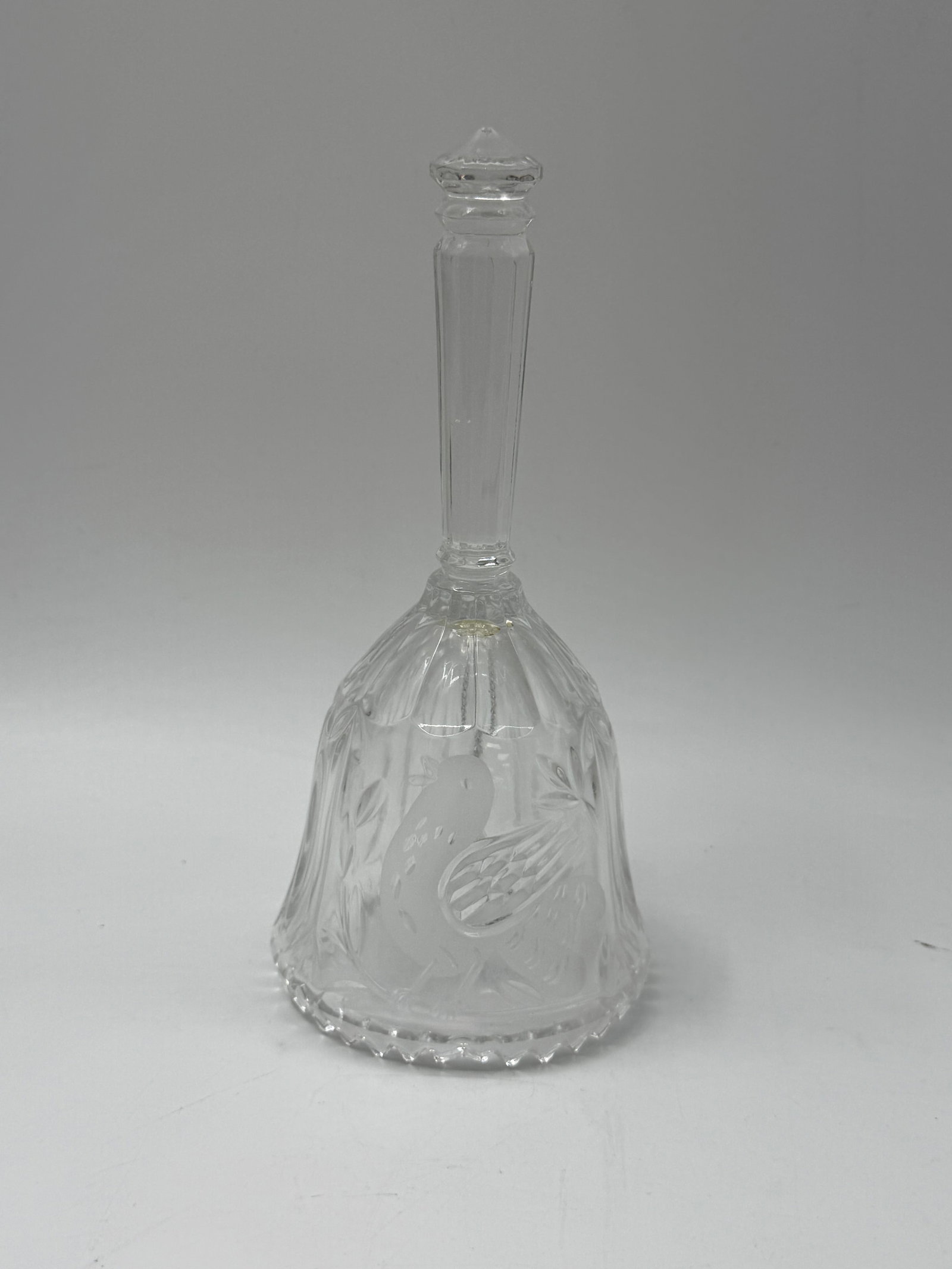 Etched Crystal Hand Bell with Bird Motif: Clear crystal hand bell featuring an etched bird design. The bell has a slender handle and a scalloped base. Includes clapper.