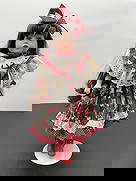 Porcelain Doll in Strawberry Print Dress with Red Boots: This vibrant porcelain doll features long dark brown hair, striking green eyes, and bright red lips. She is dressed in a red and green strawberry-themed dress with a white eyelet lace collar,