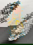 Porcelain Doll in Blue Daisy Dress with Bonnet: This cheerful porcelain doll features long blonde braids, blue eyes, and a bright smile. She is dressed in a blue daisy-print dress with an ivory eyelet apron, accented with yellow and blue ribbon