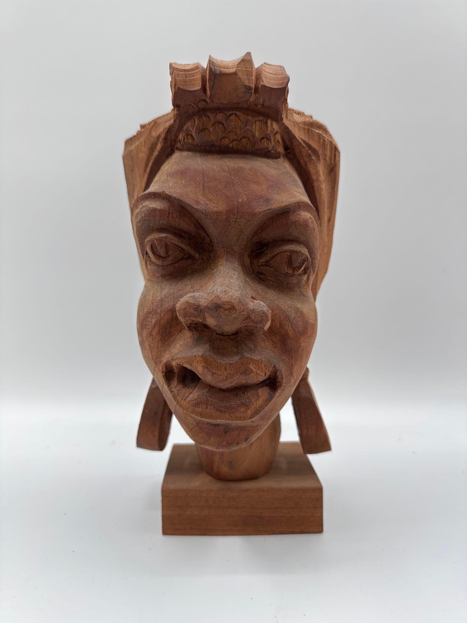 Hand-Carved Wooden Bust: Rough-carved wood sculpture of a woman's head featuring stylized facial features and an elaborate headdress. Likely folk art or tribal-inspired work. Medium: carved hardwood. No artist shown. &nbs