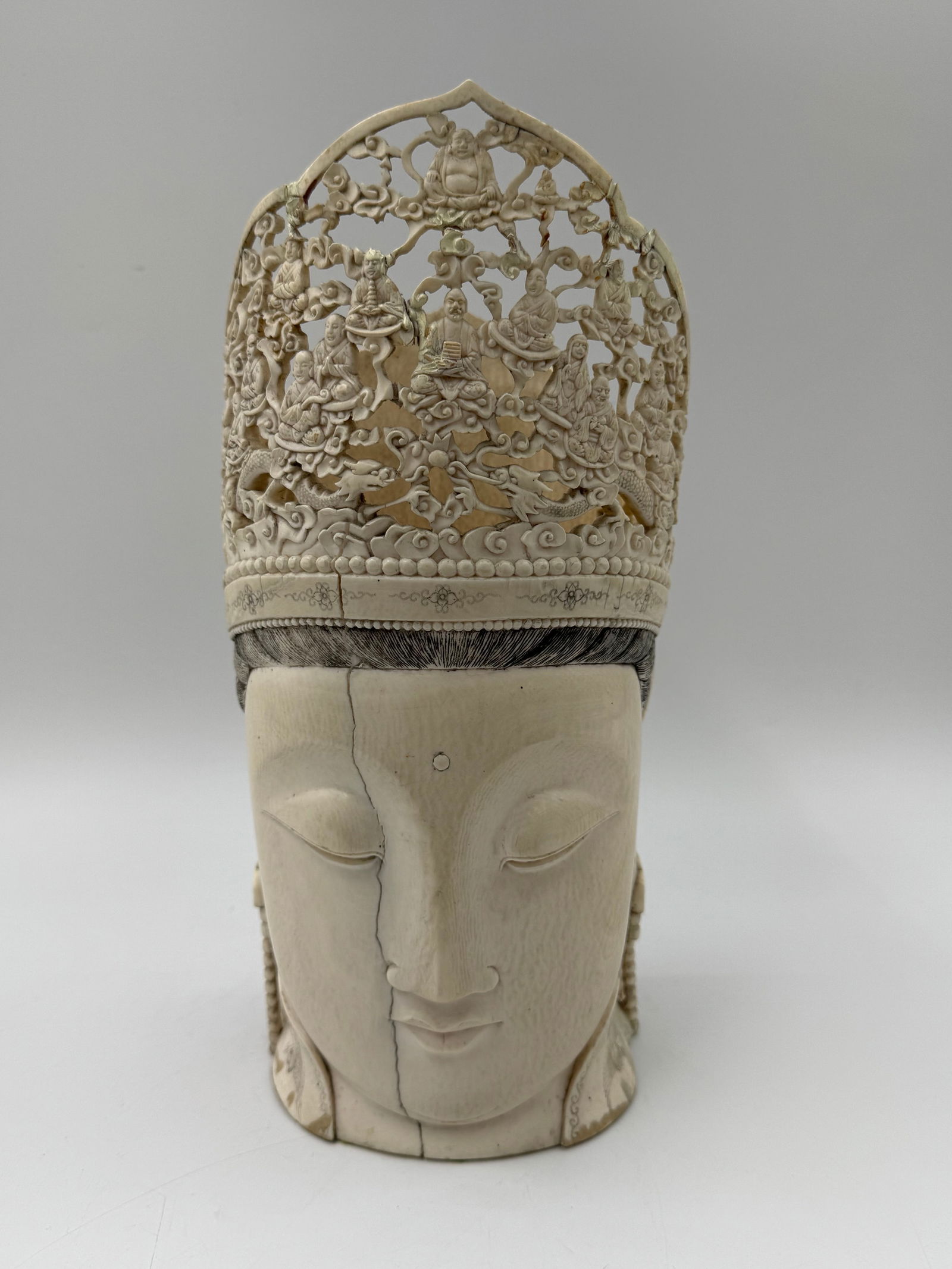 Carved Buddha Head Vase: A carved vase in the form of a Buddha head with intricate crown details. The piece measures approximately 13 x 5.5 inches. Decorative and unique.