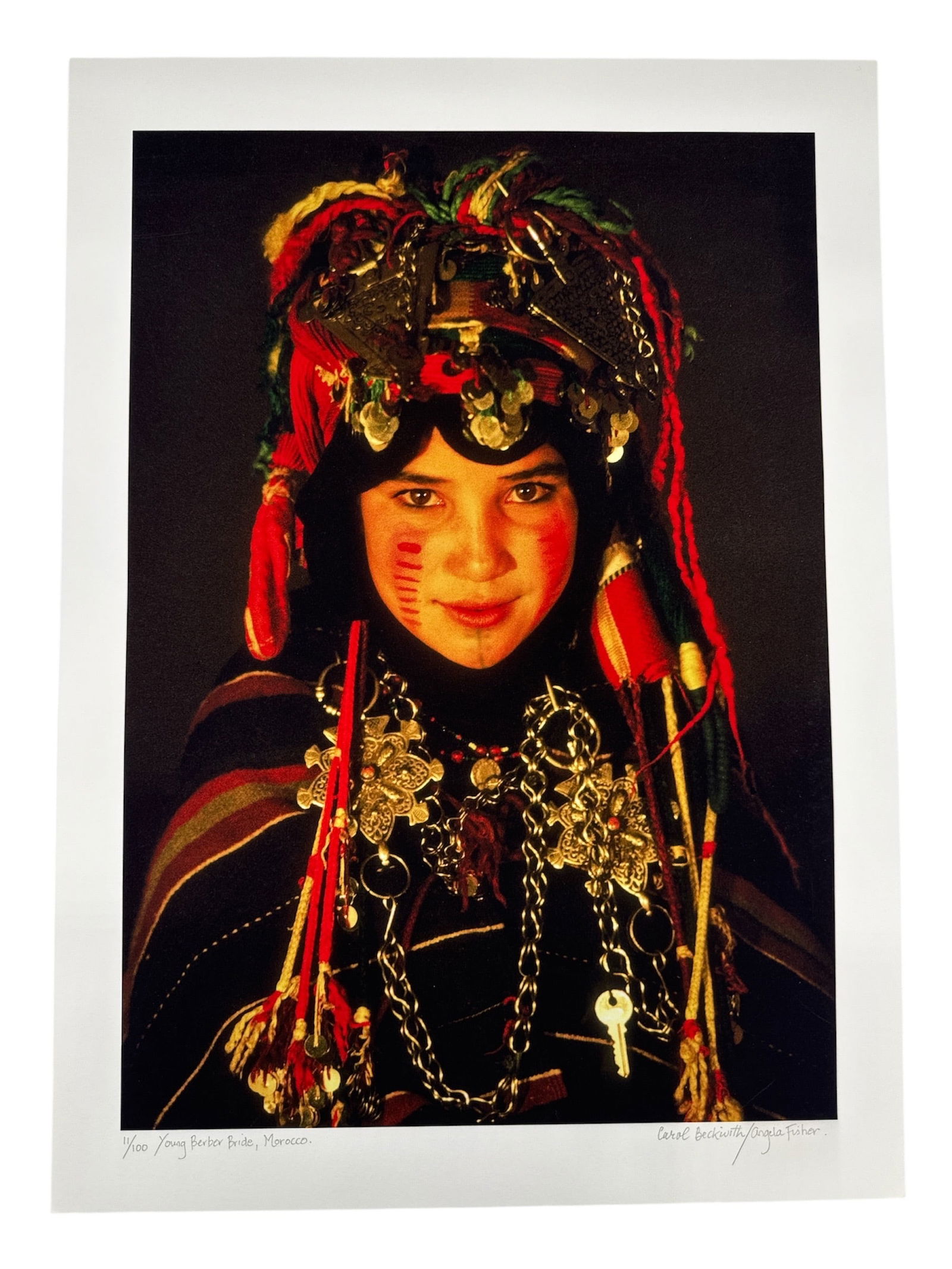 Young Berber Bride, Morocco Photograph by Angela Fisher and Carol Beckwith: Color photographic portrait depicting a young Berber bride from Morocco, shown wearing traditional ceremonial attire, elaborate headdress, and ornate jewelry. The image is rich in color and cultural d