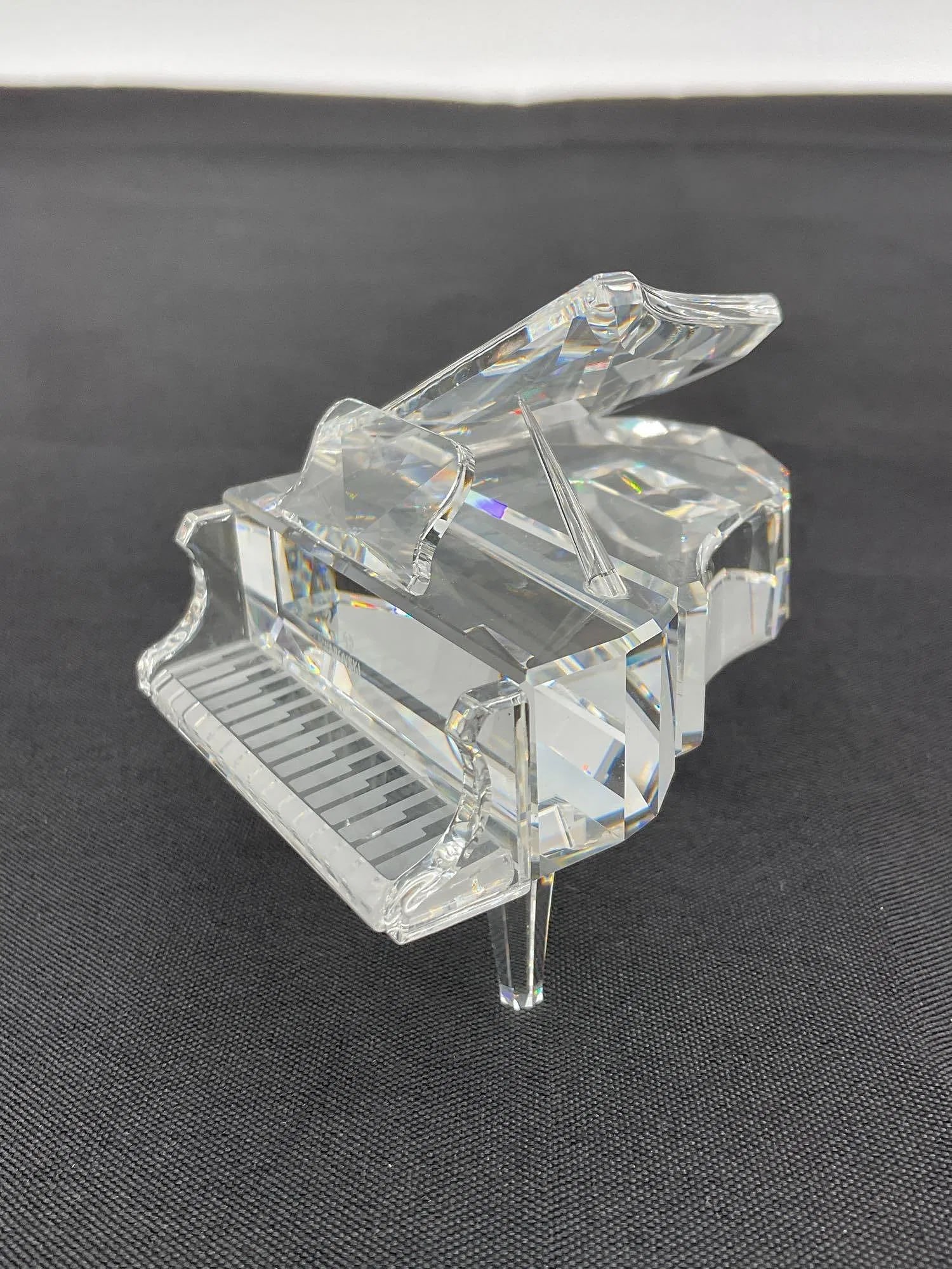 Swarovski Crystal Grand Piano: Clear faceted crystal miniature grand piano. Highly detailed and reflective, showcasing Swarovski’s signature craftsmanship.Dimensions: piano H3in L3in W3inMedium: Swarovski crystal