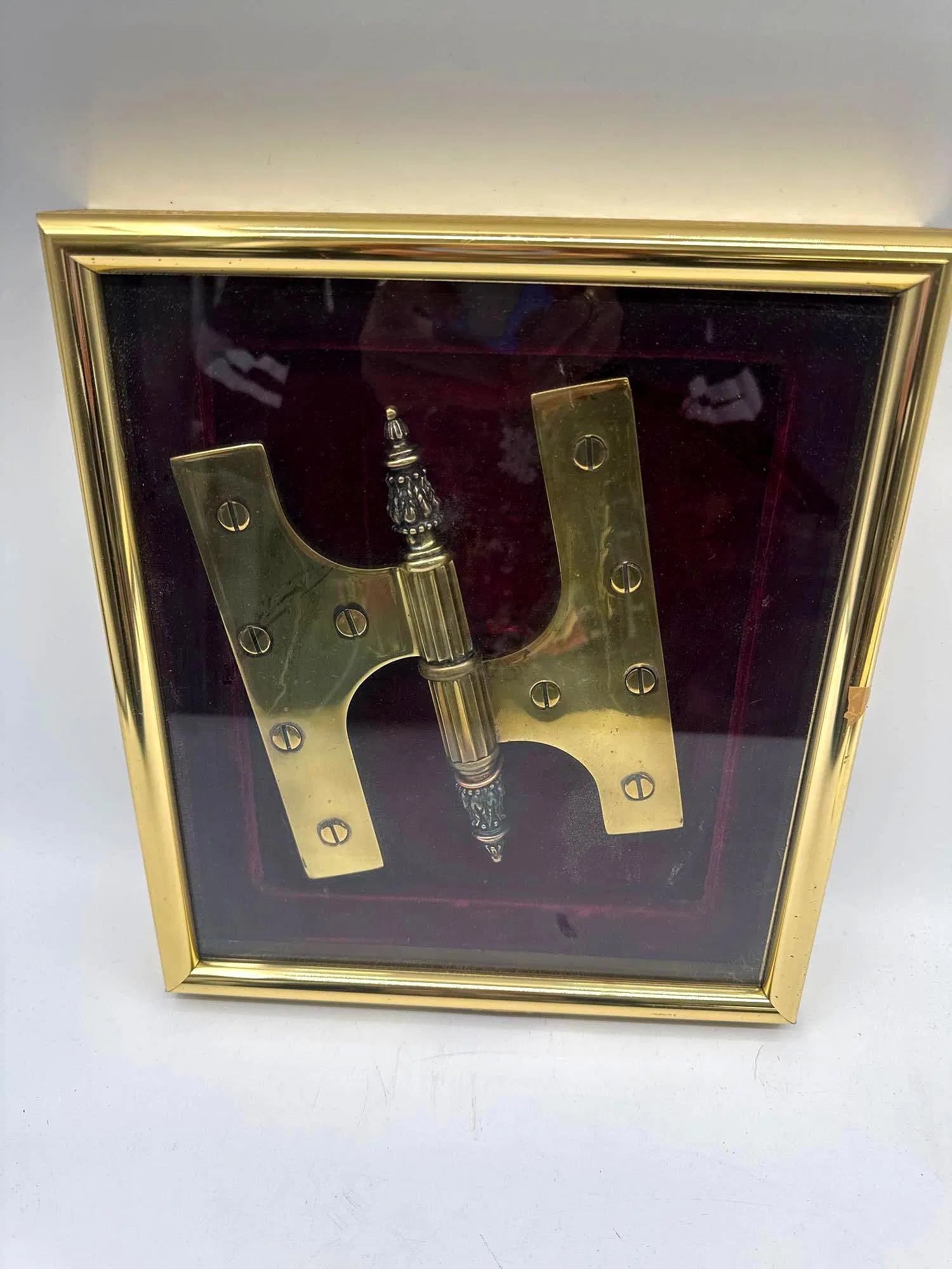 Vintage Framed Ornamental Brass Door Hinge: Large decorative brass door hinge with ornate finial, mounted on a velvet backing and enclosed in a brass frame. Likely a presentation or display piece showcasing craftsmanship, often associated with