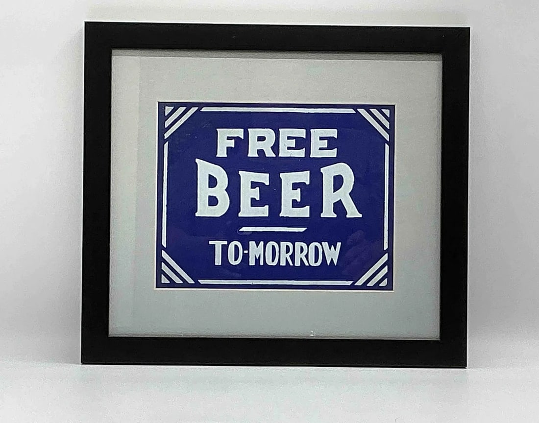 Framed Sign Print "Free Beer To-morrow": Humorous novelty print reading Free Beer To-morrow in bold white lettering against a blue background with decorative border. Framed under glass with a simple black frame. Popular as