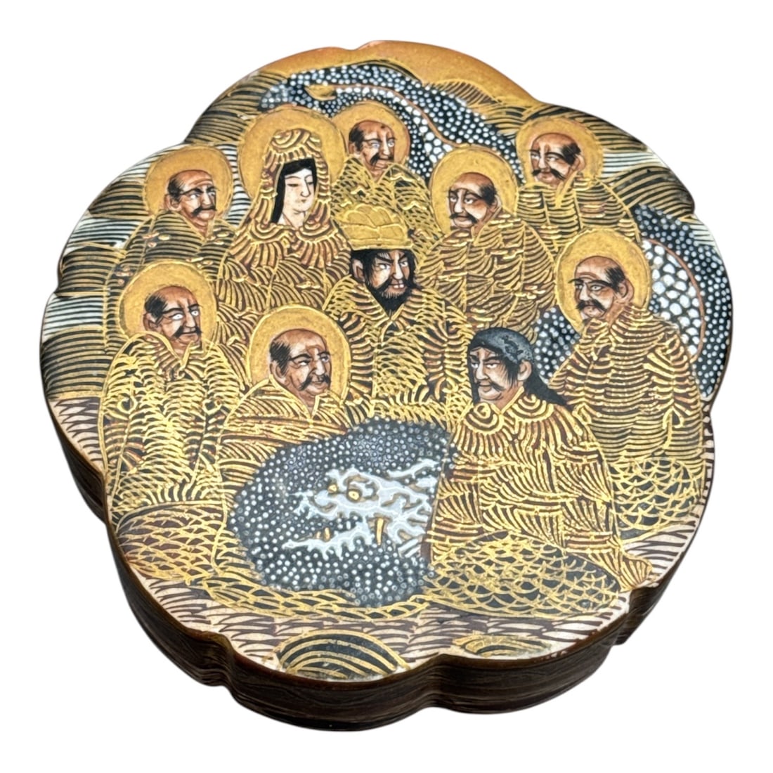 Japanese Satsuma Meiji Period Covered Box with Immortals Decoration: This finely decorated Japanese Satsuma style covered box features a scalloped form and intricate hand-painted scene of robed figures with gilt and cobalt detailing. The lid displays a gathering of hal