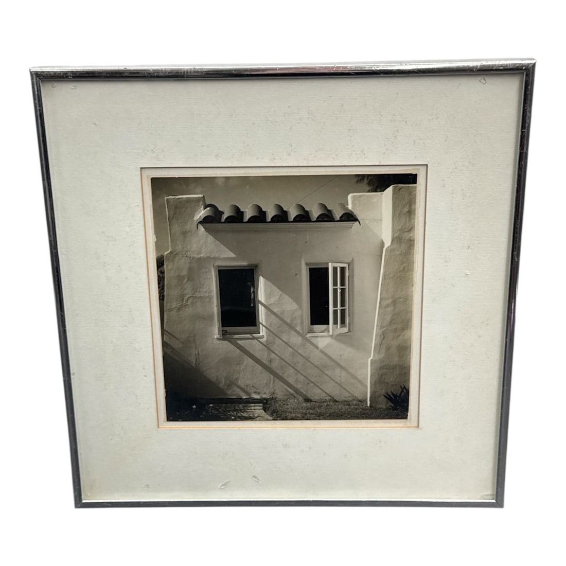 Striking Black and White Architectural Photograph, Spanish Colonial Style, Framed: This black and white photograph captures a minimalist architectural façade featuring stucco walls, a tiled roofline, and two contrasting windows, rendered with strong light and shadow. The comp
