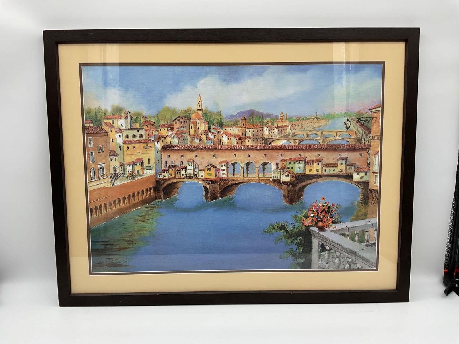 Ponte Vecchio Florence scene by G. Spinelli: Colorful painting of the iconic Ponte Vecchio bridge in Florence, Italy, with charming riverside buildings and distant hills. A vibrant floral arrangement in the foreground adds depth and warmth.