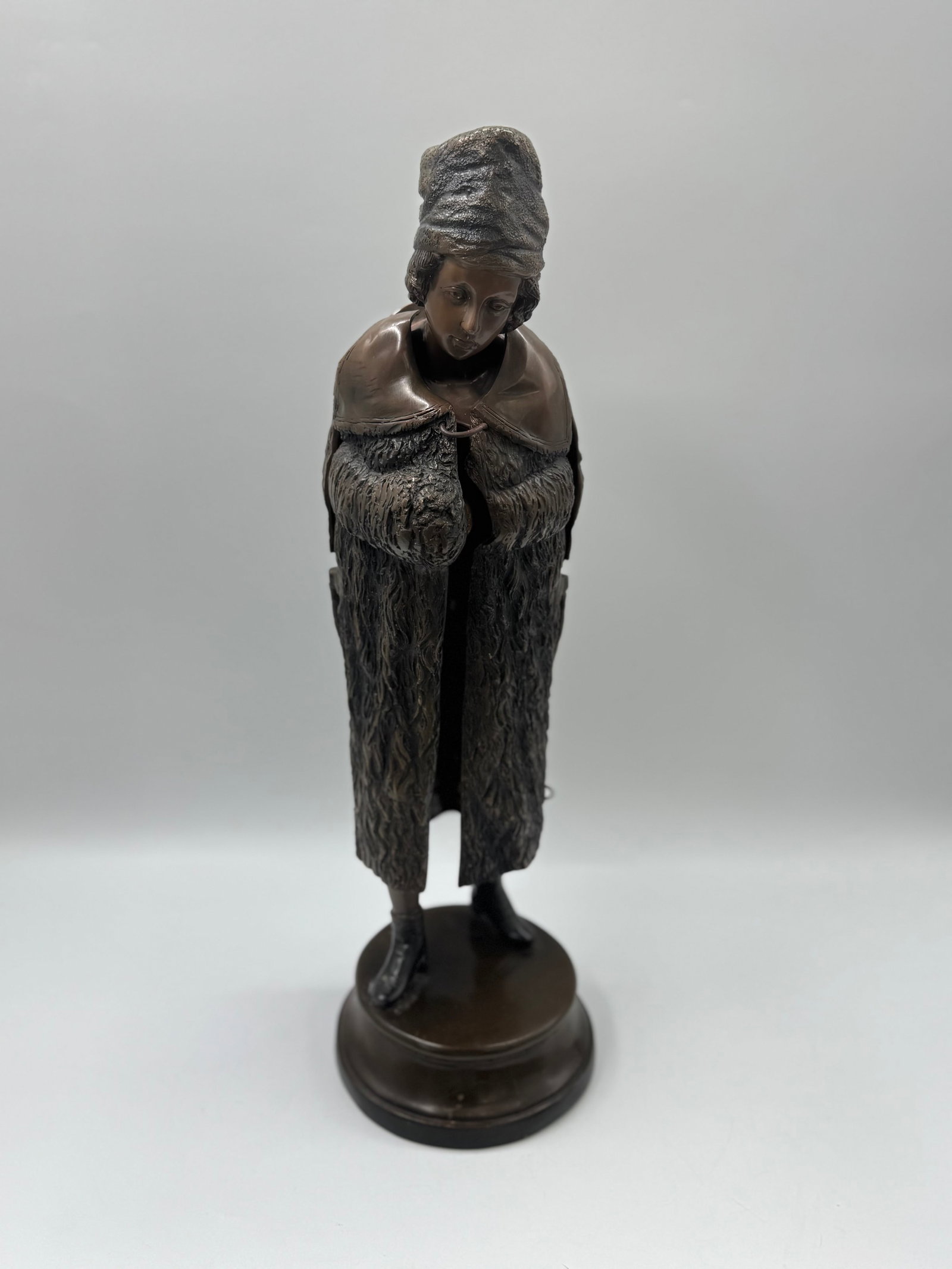 Bronze Nude Female Figure with Hinged Cloak: A finely crafted bronze sculpture depicting a standing nude woman, partially concealed by a hinged cloak that opens to reveal the full figure. The figure wears a head wrap and stands on a round