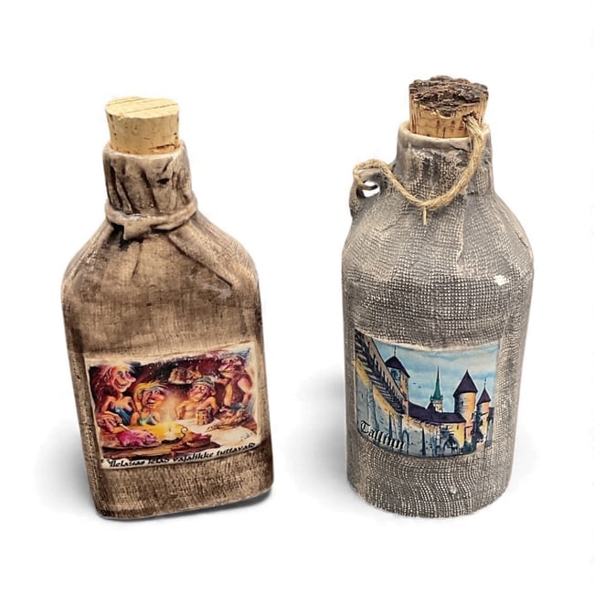 Pair of Vintage Souvenir Wrapped Bottles: A set of two decorative souvenir bottles, each wrapped in textured fabric with applied scenic labels. One features a medieval village illustration while the other shows a rustic tavern scene. Both are