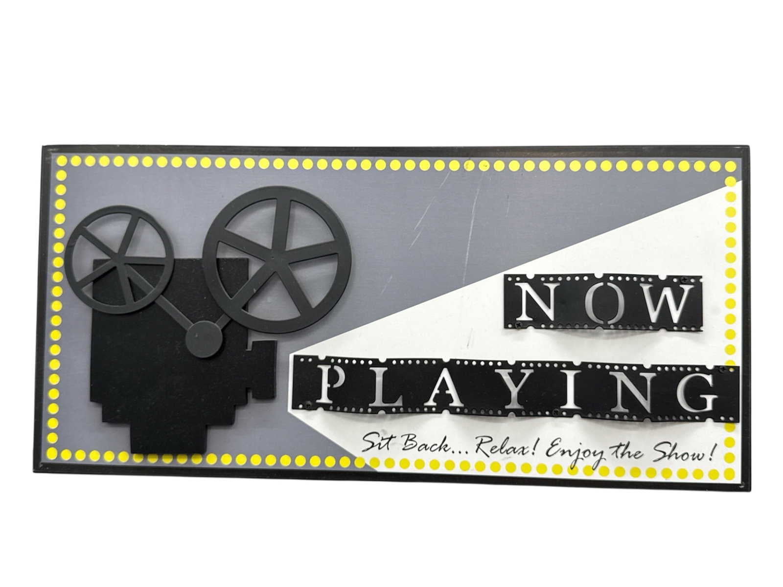 Now Playing Decorative Wall Sign with Film Reel Motif: Decorative wall sign featuring the phrase Now Playing with a stylized film reel and projector motif, accented by marquee-style dots and graphic typography. The design evokes a classic movie theater th