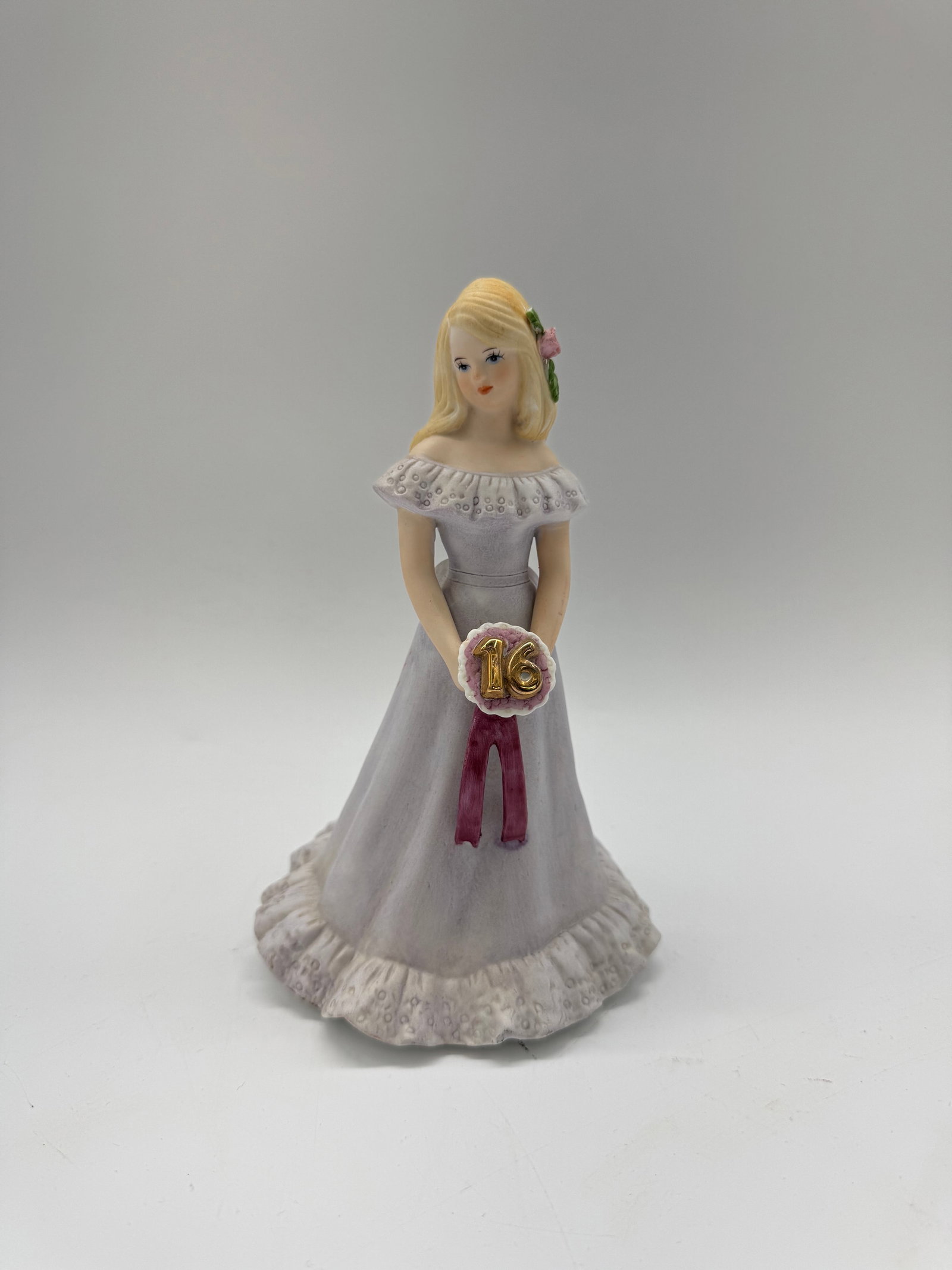 Enesco Sweet Sixteen Musical Figurine: Enesco 'Sweet Sixteen' musical figurine. Depicts a young woman in a gown holding a '16' sign. Measures approximately 7.5 inches tall and 5 inches wide. Marked on the base.