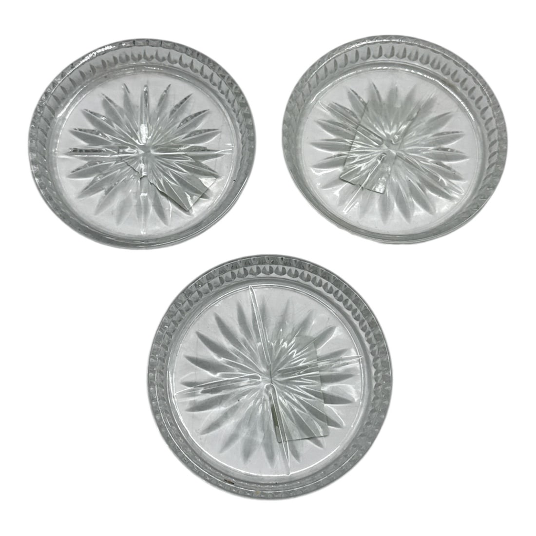 Set of Three Cut Crystal Coasters with Starburst Design: Elegant set of three small cut crystal coasters featuring a central starburst motif surrounded by a decorative patterned rim. The faceted design catches and reflects light beautifully, making these id