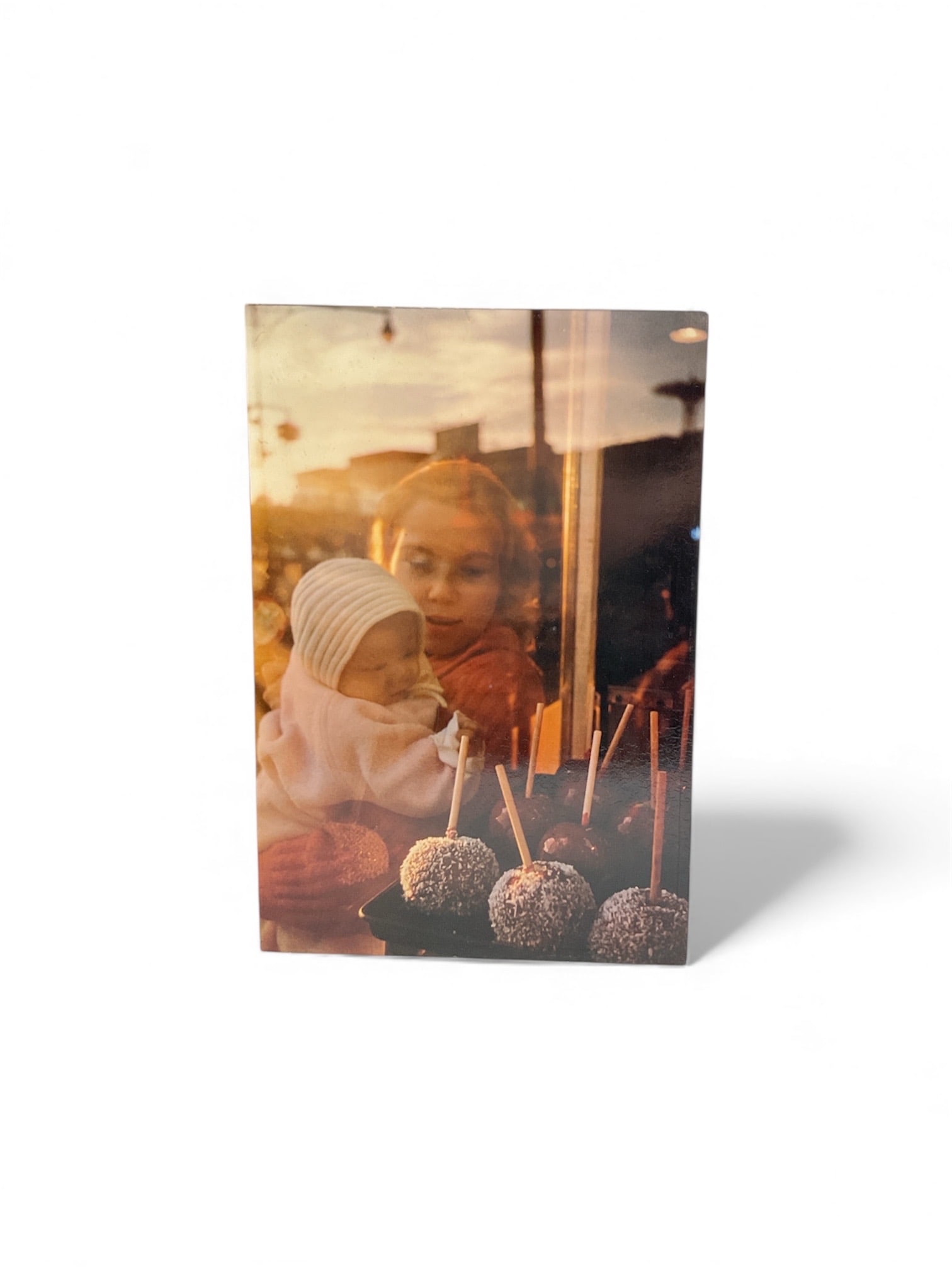 Vintage Framed Photograph of Child at Candy Apple Stand, Mid-20th Century: This vintage photographic print depicts a young child gazing through a shop window at candy apples on sticks, a nostalgic and evocative street-scene composition. The warm tones and reflective glass cr