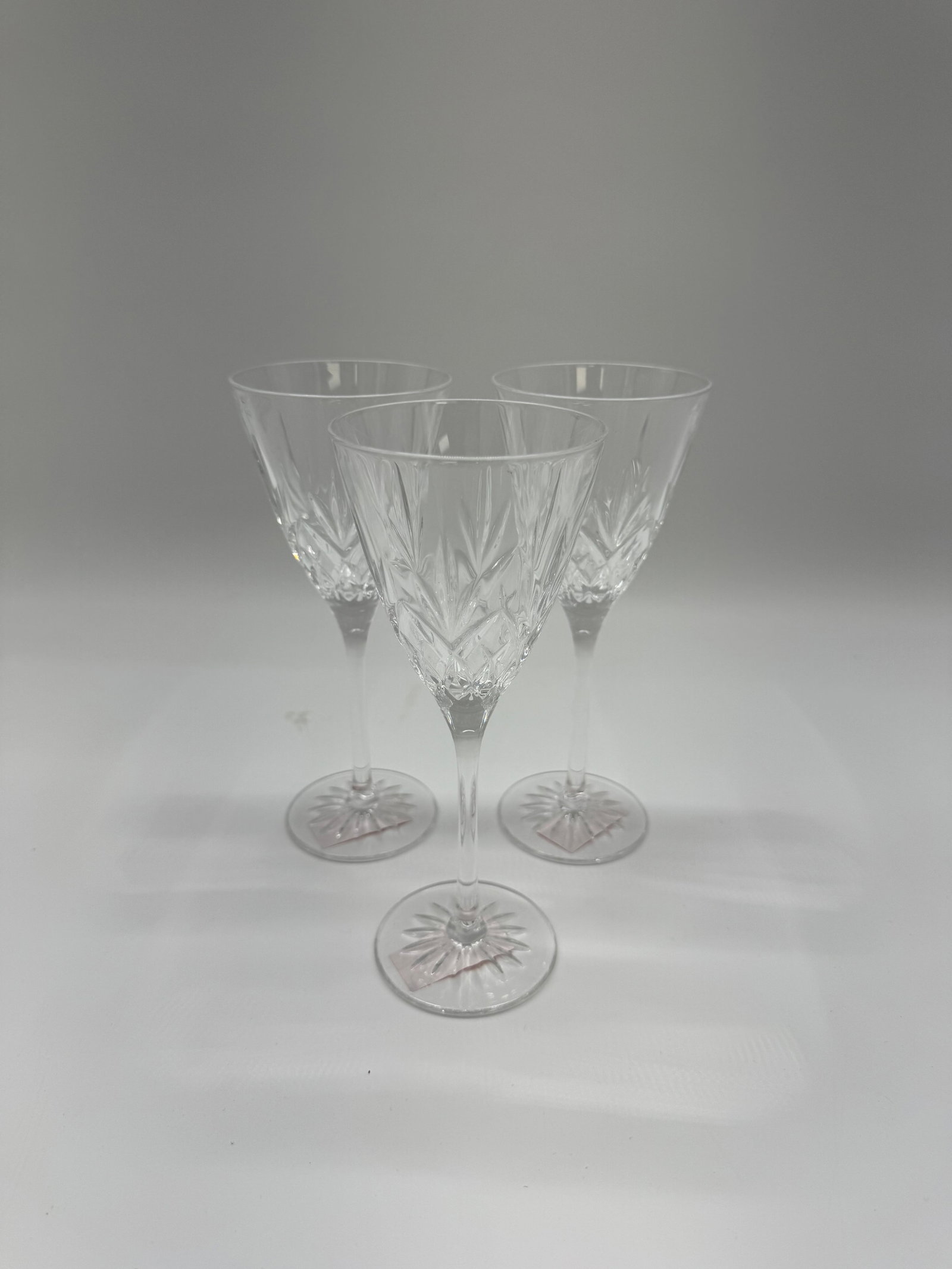 Set of Three Crystal Champagne Flutes: Set of three crystal champagne flutes. Each flute features a detailed cut crystal design on the bowl and a starburst pattern on the base. Dimensions: H: 7.5in W: 3in