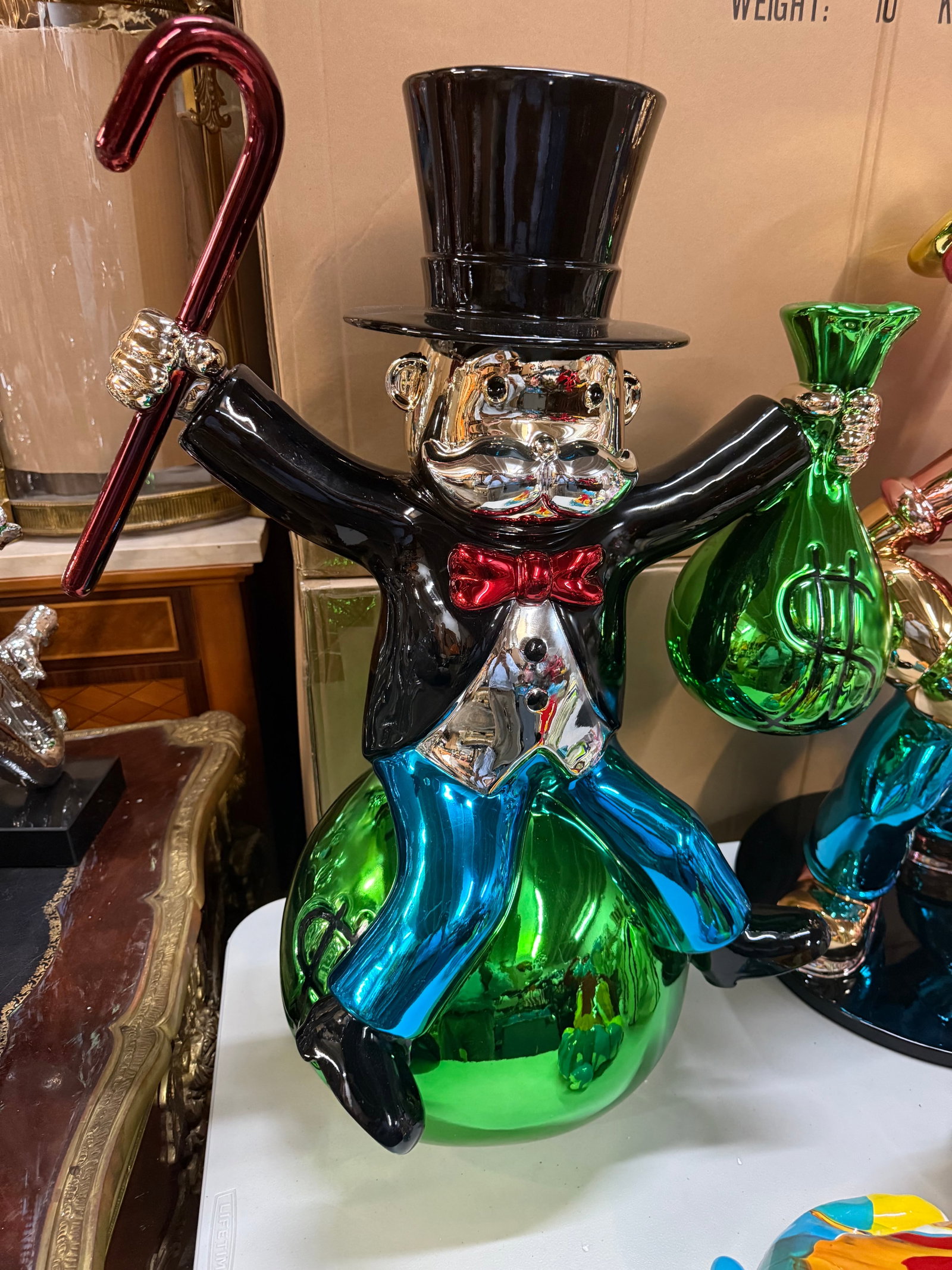 "Joyous Monopoly Man Sitting on Money Bag" Alec Monopoly Inspired Pop Art Statue | Chrome Finish: Description:This striking, large-format sculpture of the iconic Monopoly Man (Rich Uncle Pennybags, or Mr. Monops) is a vibrant piece of pop art home decor. Inspired by the street art