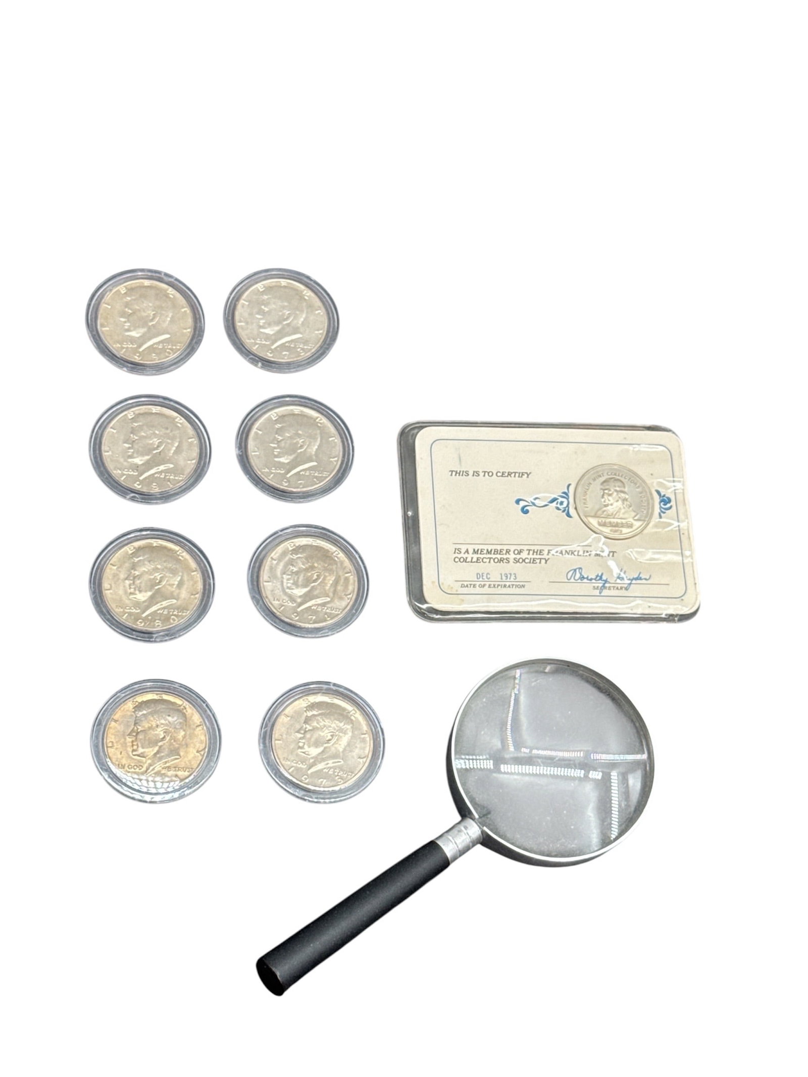Collection of Kennedy Half Dollars with Magnifier and Certificate: Group of Kennedy half dollars housed in protective plastic capsules, accompanied by a small magnifying glass and a certificate card (as shown). Coins feature the profile of John F. Kennedy; dates and