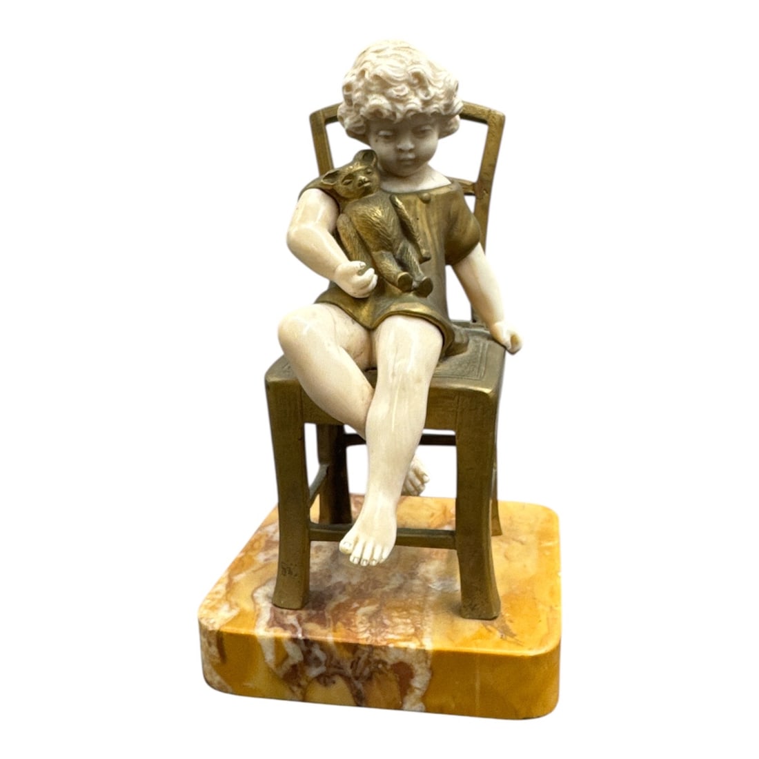 L. Barthelemy Bronze and Ivory Style Figurine of Child Seated on Chair: This charming figural sculpture by L. Barthelemy depicts a young child seated casually on a chair, captured with a playful and naturalistic pose. The piece is executed in a bronze and ivory style comb