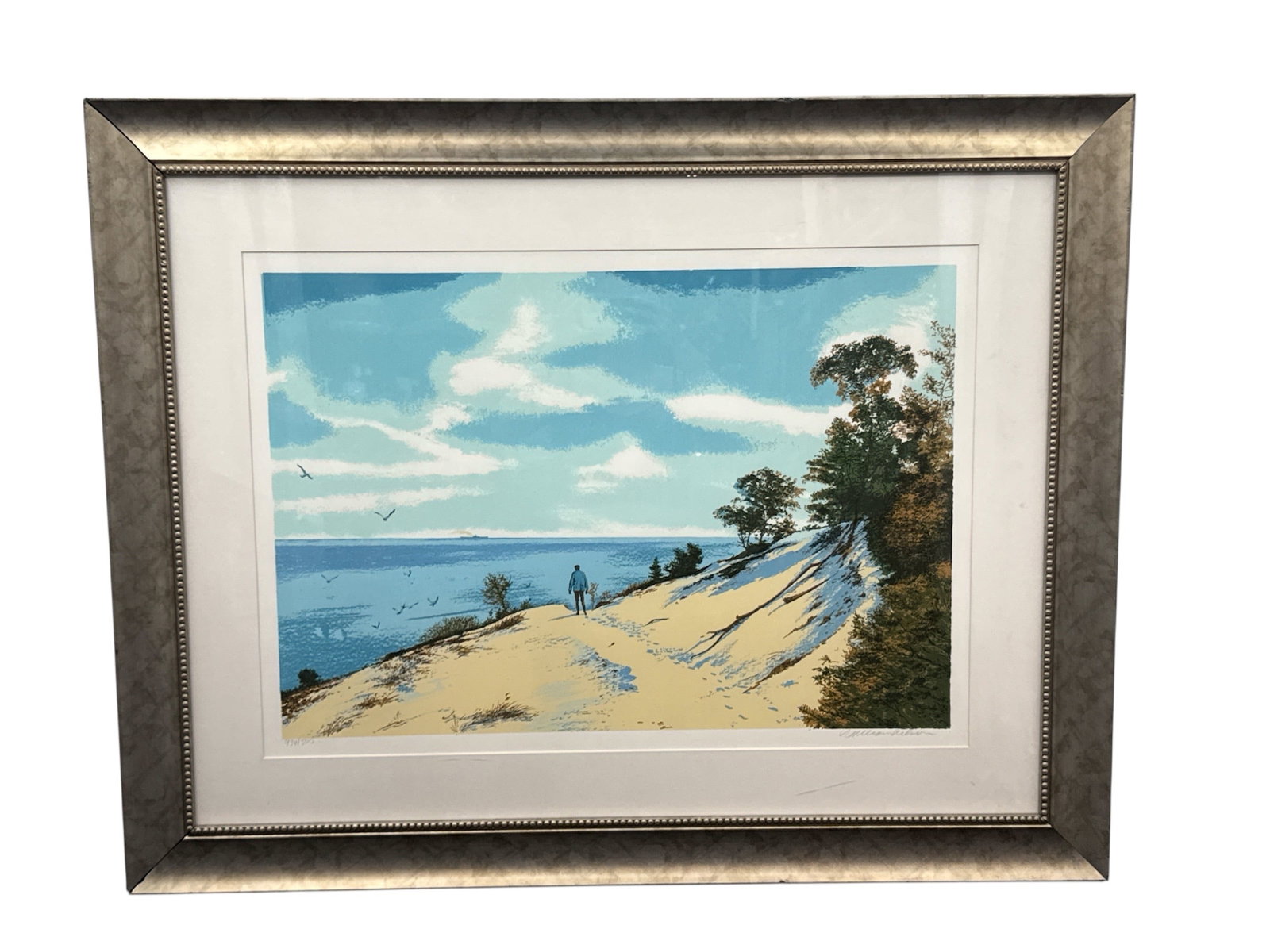 William Nelson The Dunes Limited Edition Print Framed 434/500: Limited edition print titled The Dunes by artist William Nelson. This serene coastal landscape depicts sandy dunes overlooking a calm blue shoreline beneath a bright sky with drifting clouds. Trees fr