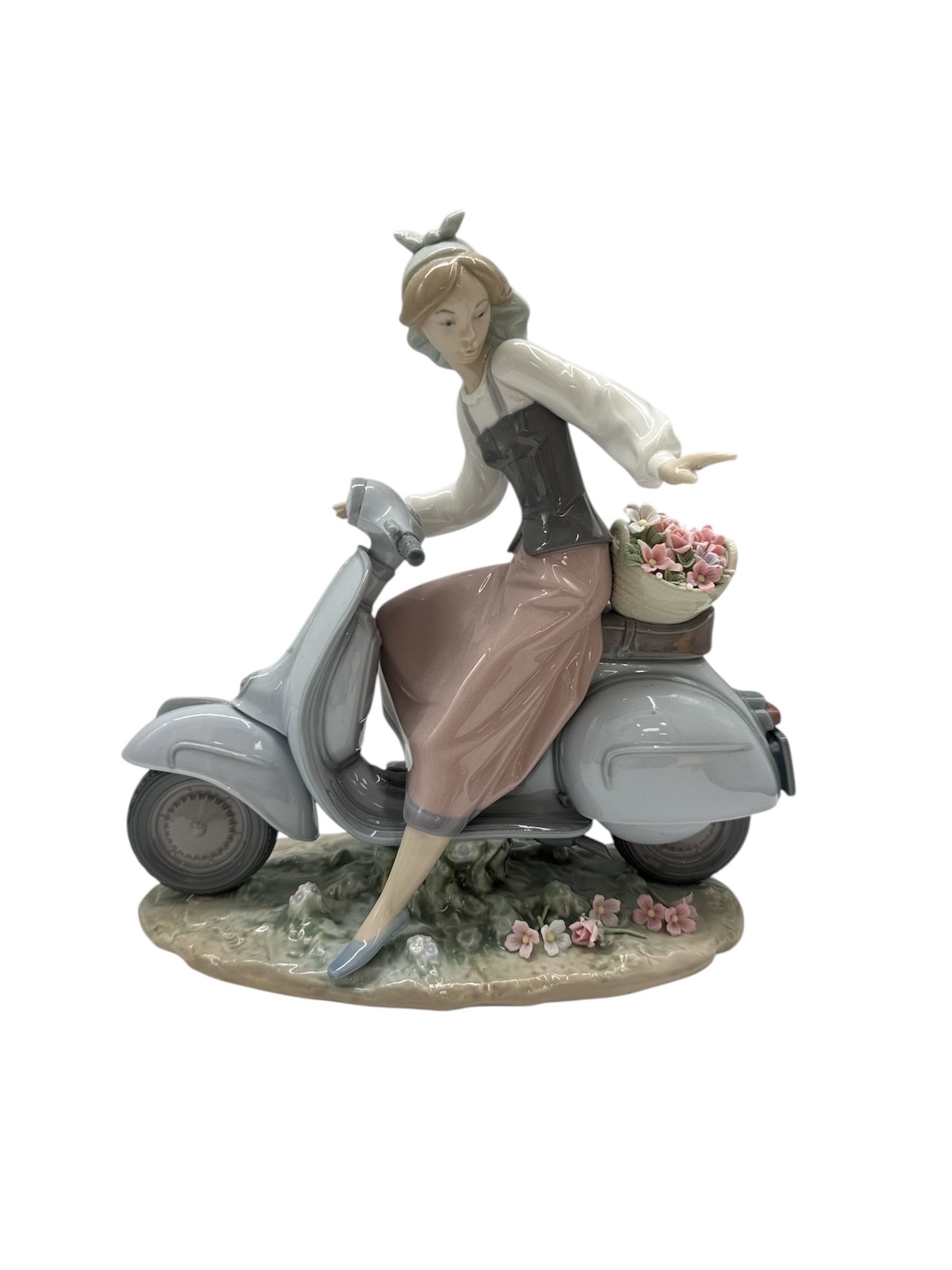 Lladro Girl on Motorbike with Flowers Porcelain Figurine 6845: This impressive and highly detailed porcelain figurine, titled Girl on Motorbike (model 01006845) and often referred to as Scooter Girl, is a vibrant example of Lladro’s contemporary narrative s