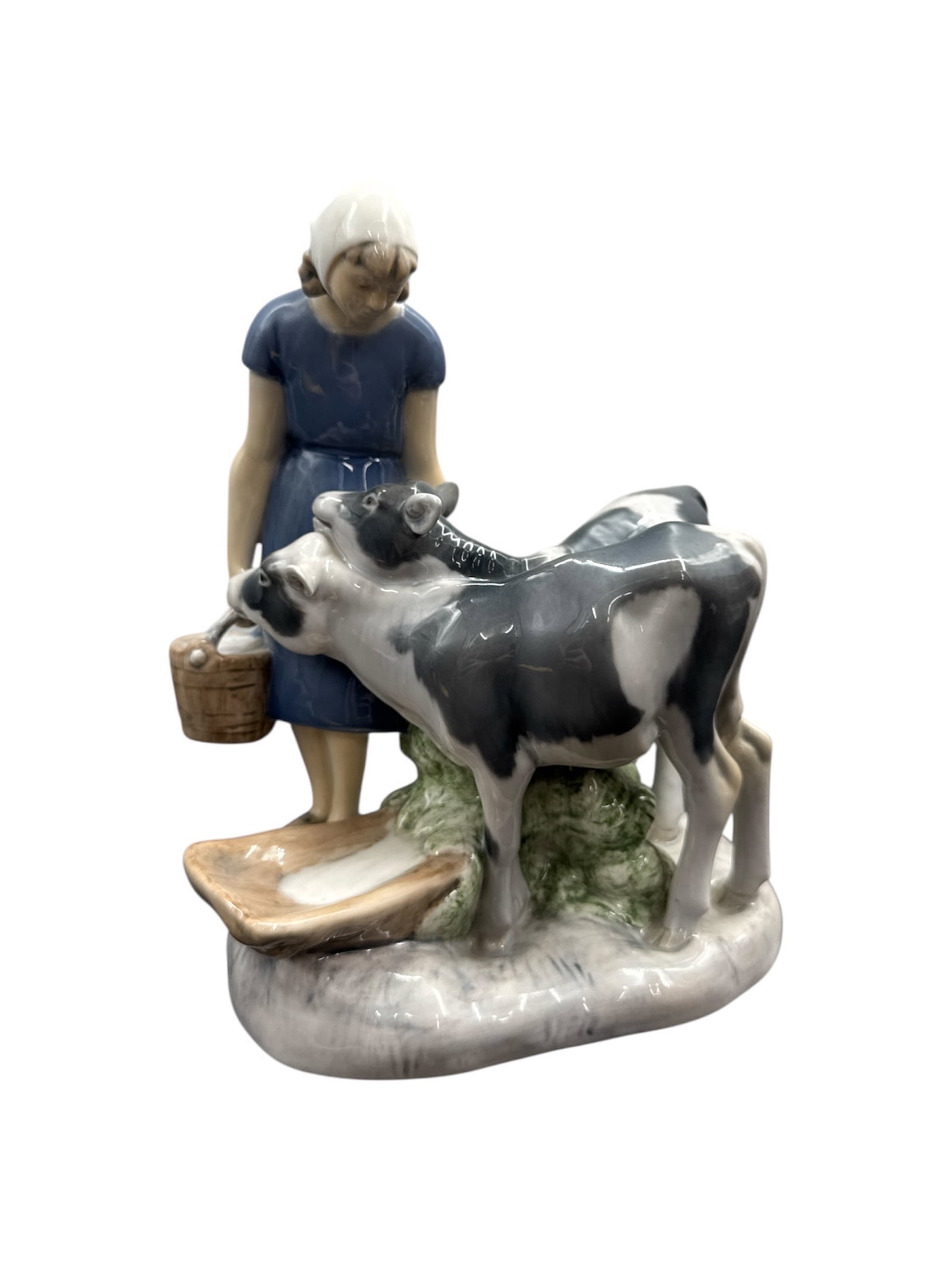 Bing & Grøndahl Porcelain Figurine Girl with Calves, Model 2270: This Bing & Grøndahl porcelain figurine titled Girl with Calves depicts a young girl standing beside two calves, holding a basket and dressed in traditional rural attire. The composition ca