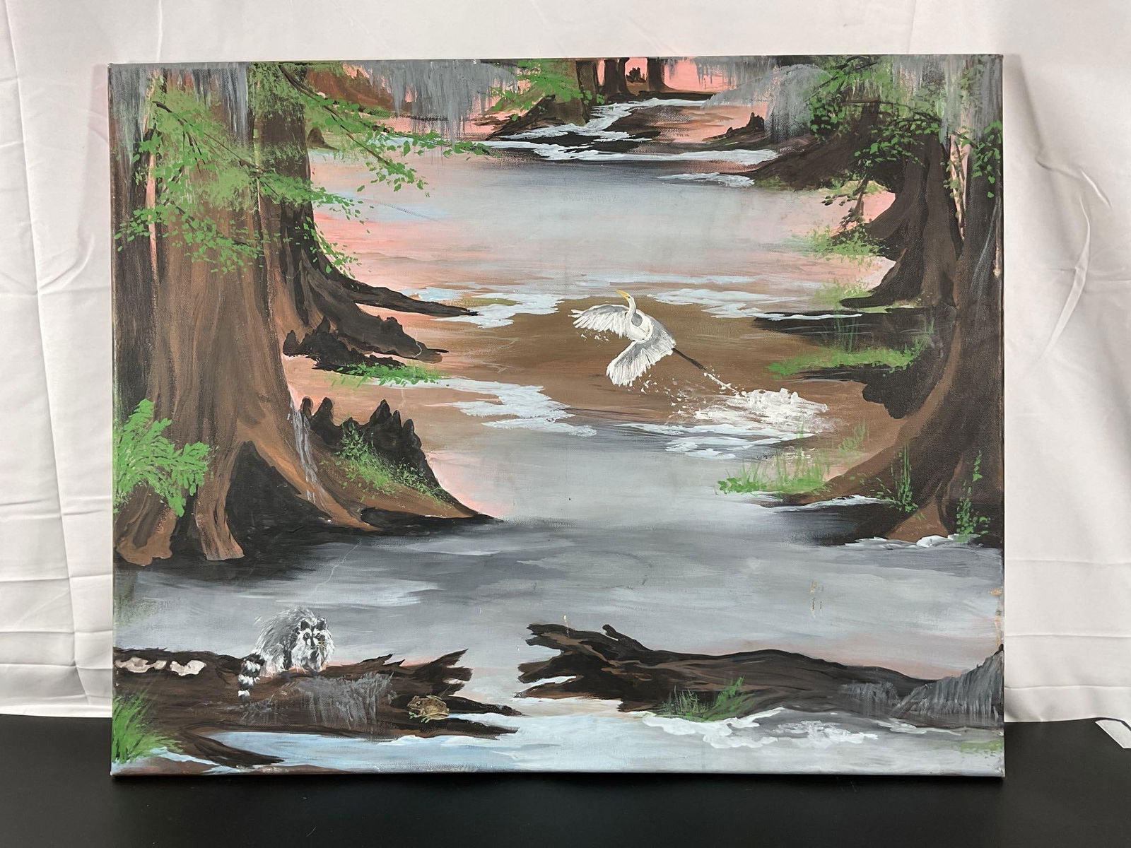 "Fish eating creek" by Sharon Dalene (American) Oil on Canvas: This serene painting captures a quiet bayou scene, featuring majestic cypress trees with hanging moss, a graceful white egret mid-flight, and gentle water reflecting the soft hues of the sky. The