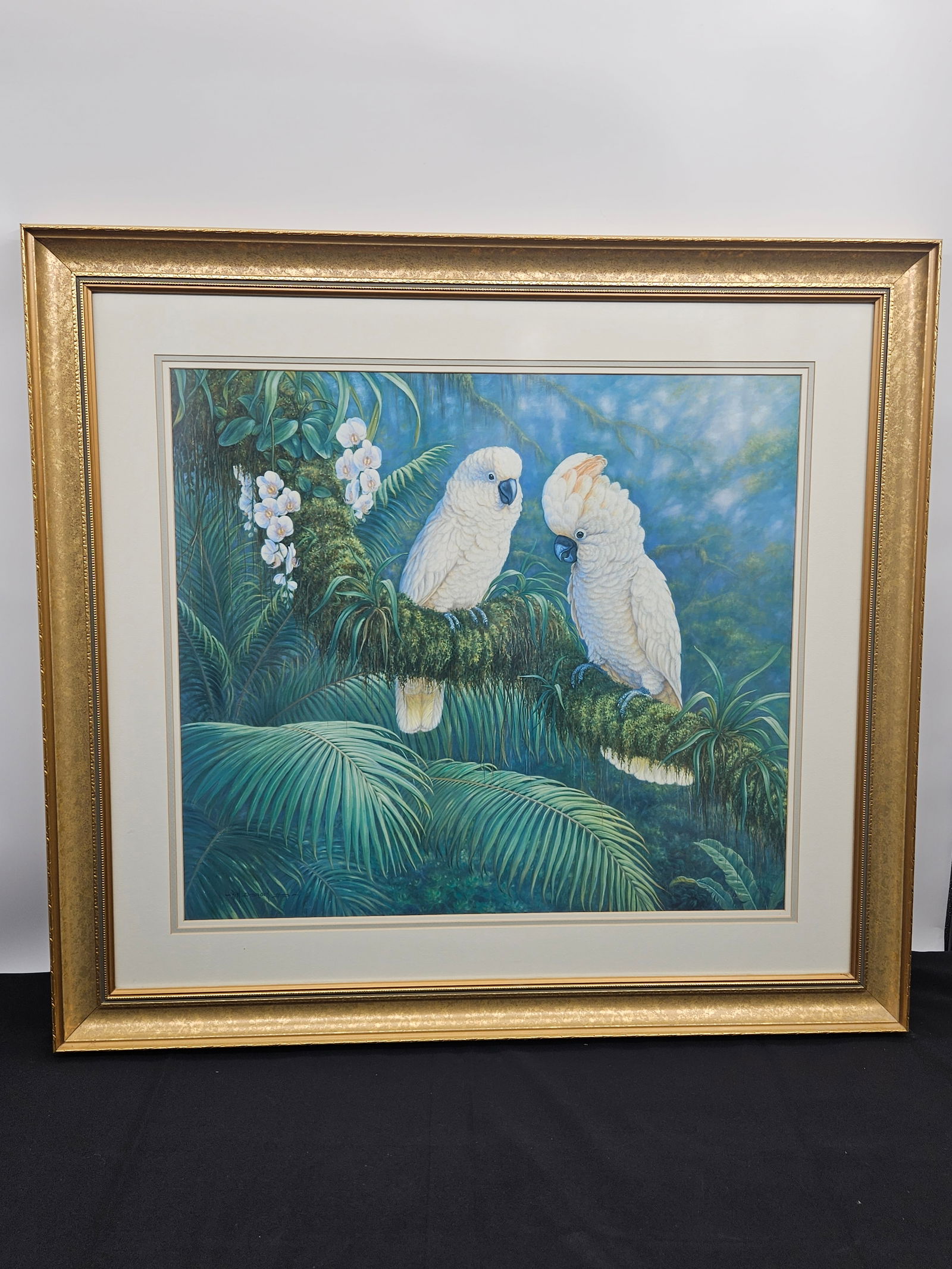 Cockatoo Courtship by Kim Brooks (England, b.1936) Serigraph: Description: Vibrant artwork by Kim Brooks depicting two white cockatoos engaging in a tender courtship moment amid a lush tropical rainforest setting. The piece captures rich texture and color
