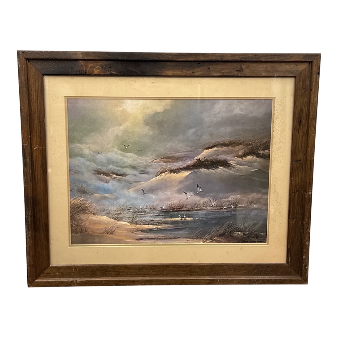 Dana Gibson Noble Framed Coastal Landscape Print: Framed coastal landscape print signed Dana Gibson Noble depicting a dramatic shoreline scene with rolling dunes, windswept grasses, and seabirds in flight over calm waters. The atmospheric composition