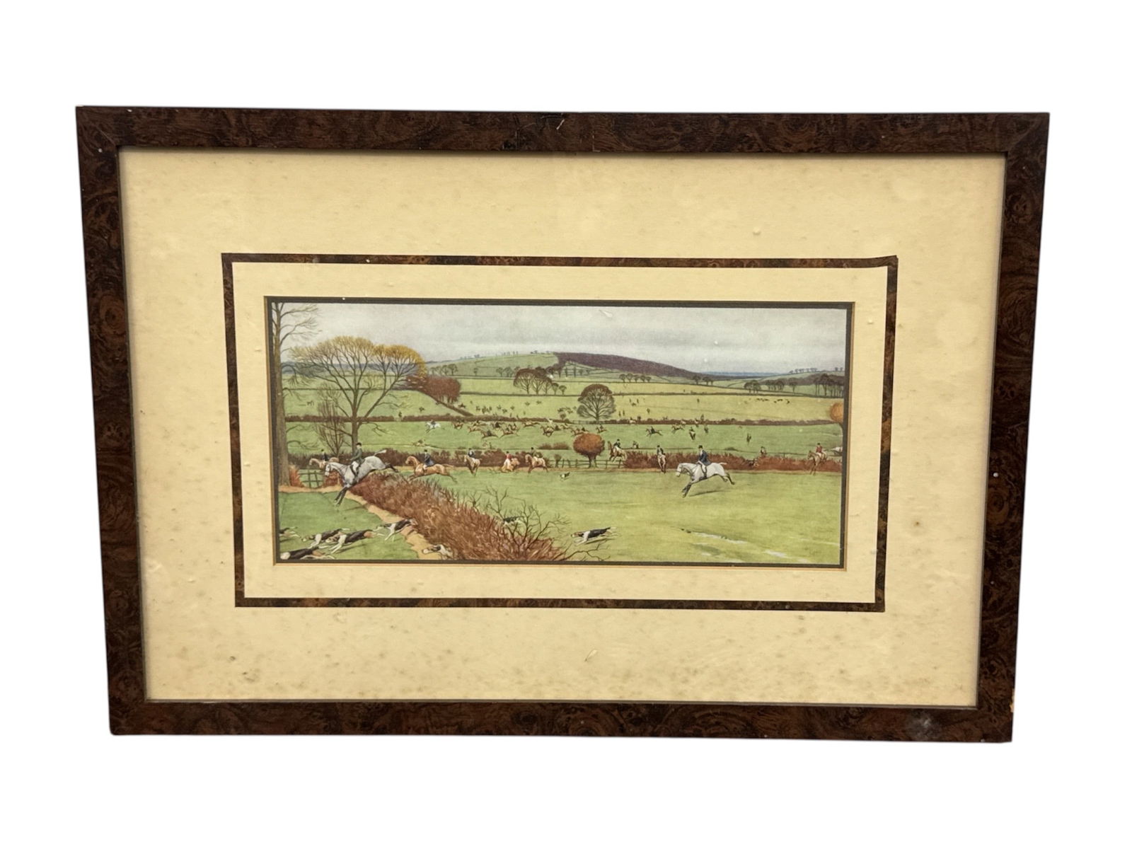 English Hunt Scene Framed Print: Framed English hunt scene print depicting riders on horseback and hounds moving through open countryside with rolling hills and pastoral landscape in the background. The composition reflects tradition