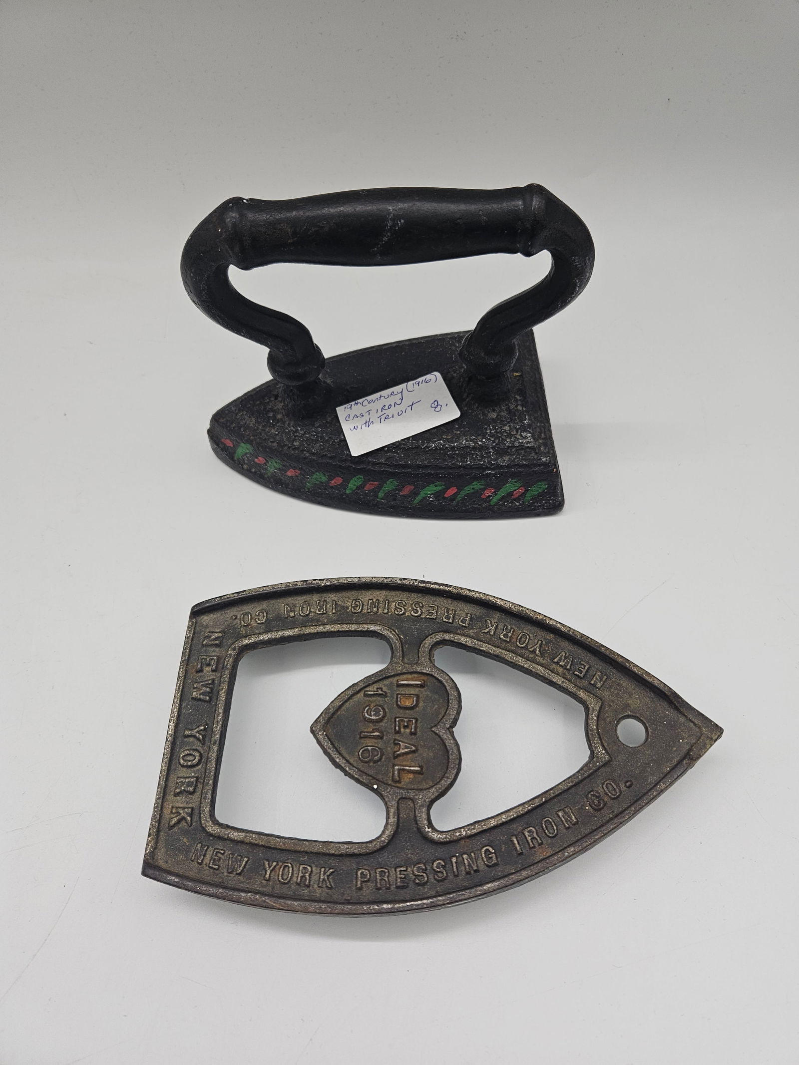 Cast Iron Trivet and Solid Old English Iron 1916: Antique cast iron set featuring a 1916 Old English solid pressing iron and a decorative trivet with heart-shaped center. A fine example of early 20th-century household craftsmanshipiron Dimensions: