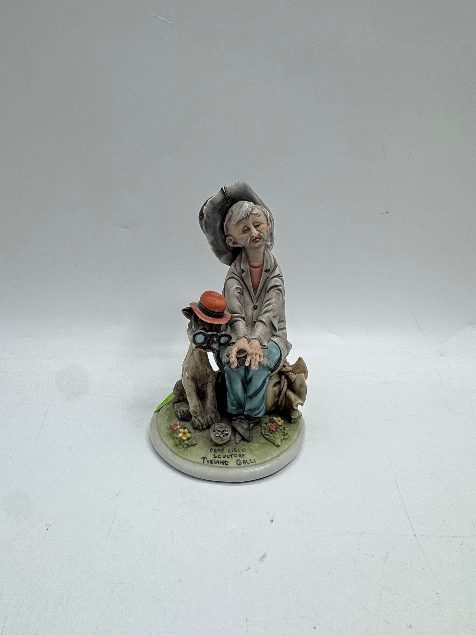 Tiziano Galli Capodimonte Italian Porcelain Figurine: Goebel figurine titled 'The Old Storyteller'. Depicts an elderly man with a hat, bag, and binoculars. Marked on the base. Dimensions: Measures approximately 8 x 5 inches.