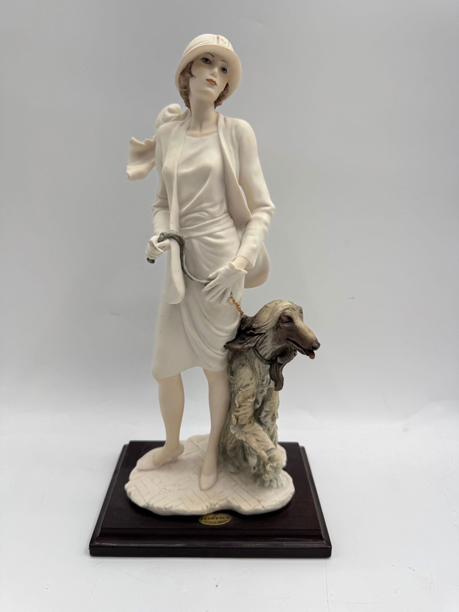 Giuseppe Armani Figurine - Lady with Dog: Giuseppe Armani figurine depicting a lady with a dog. Marked 'Florence' and signed. Mounted on a wooden base. Approximate Dimensions: 15 x 7 x 5 inches.