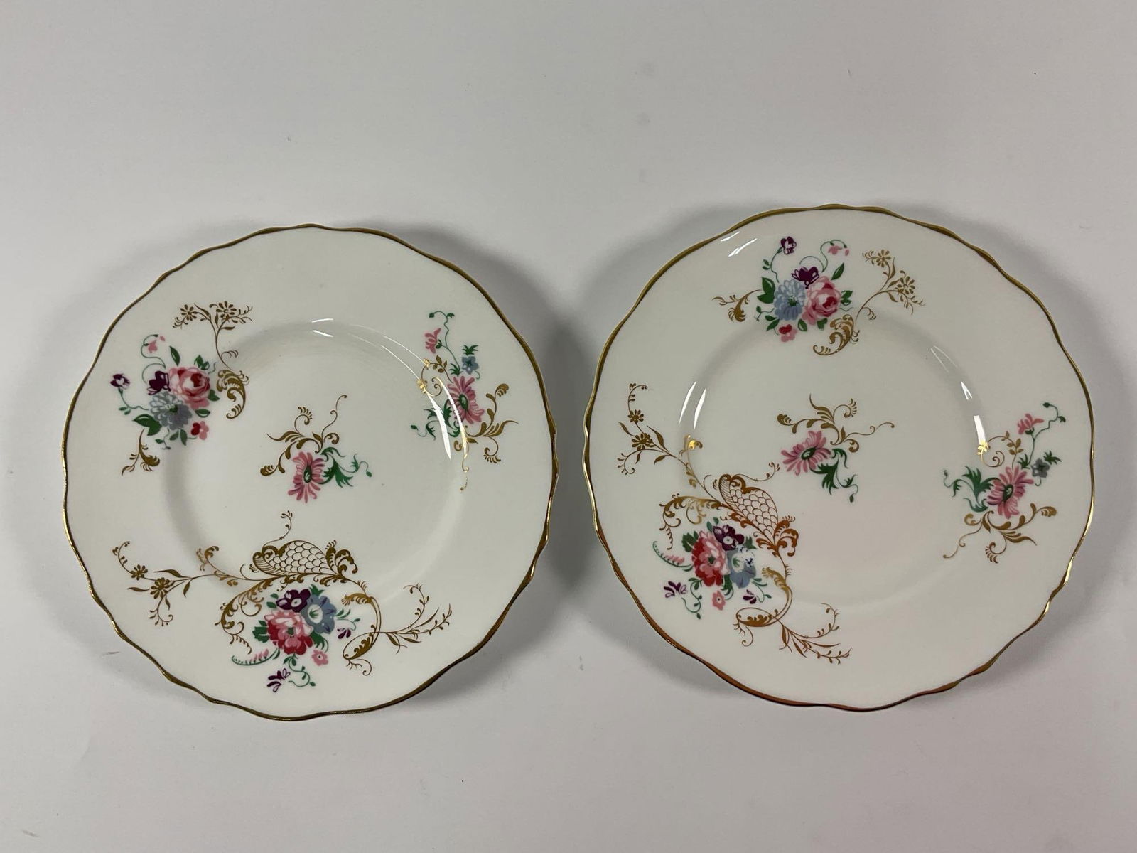 Royal Cauldon "Eugenie" Fine Bone China Dessert Plates: This is a pair of elegant fine bone china dessert plates from the "Eugenie" pattern by Royal Cauldon, England. The plates feature delicate floral bouquets in soft pastel tones, enhanced by g