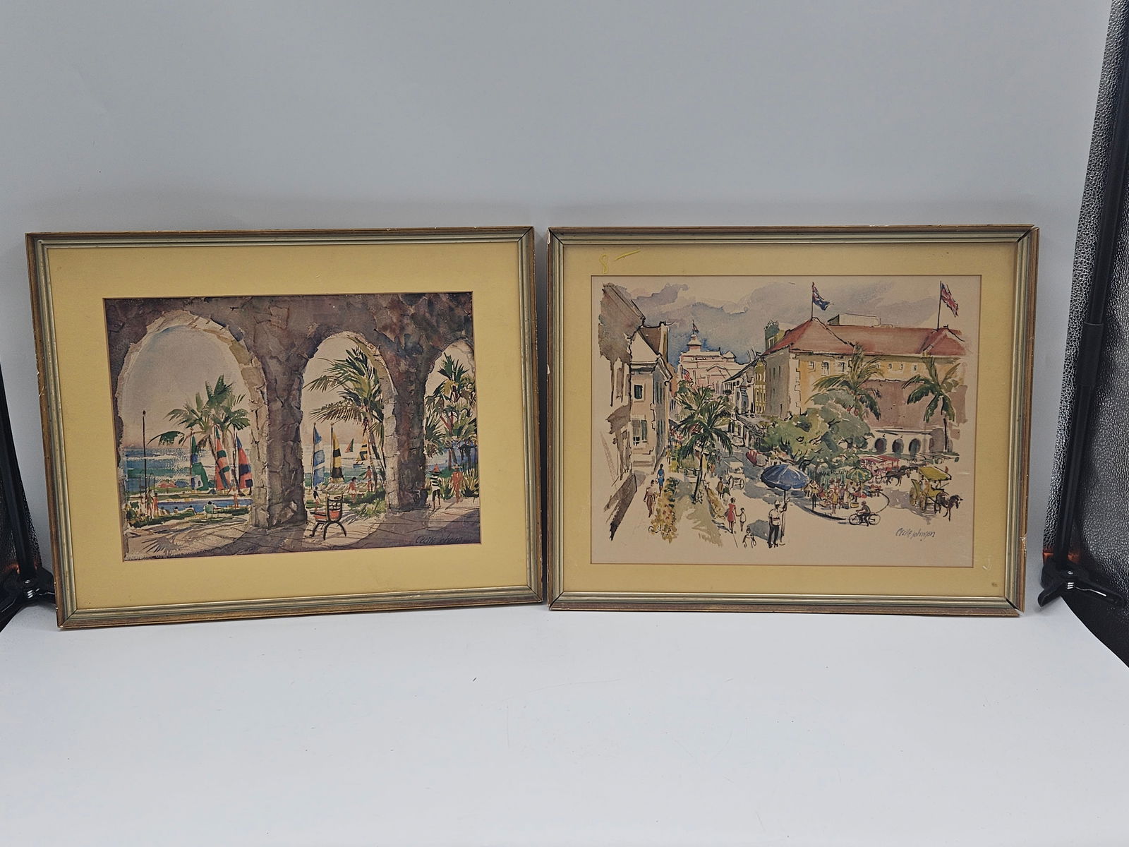 Mexican Street Scenes by Cecile Johnson: Pair of vibrant watercolor paintings depicting lively Mexican cityscapes, featuring colonial architecture, palm trees, and bustling market scenes. Cecile Johnson was known for her skillful use of