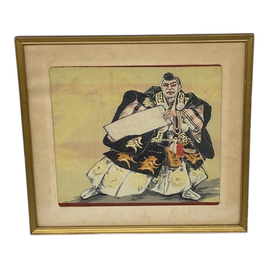 Framed Japanese Warrior Woodblock Style Print: This framed artwork depicts a traditional Japanese warrior figure rendered in a classic woodblock-inspired style, showing bold lines, expressive posture, and period attire. The composition features