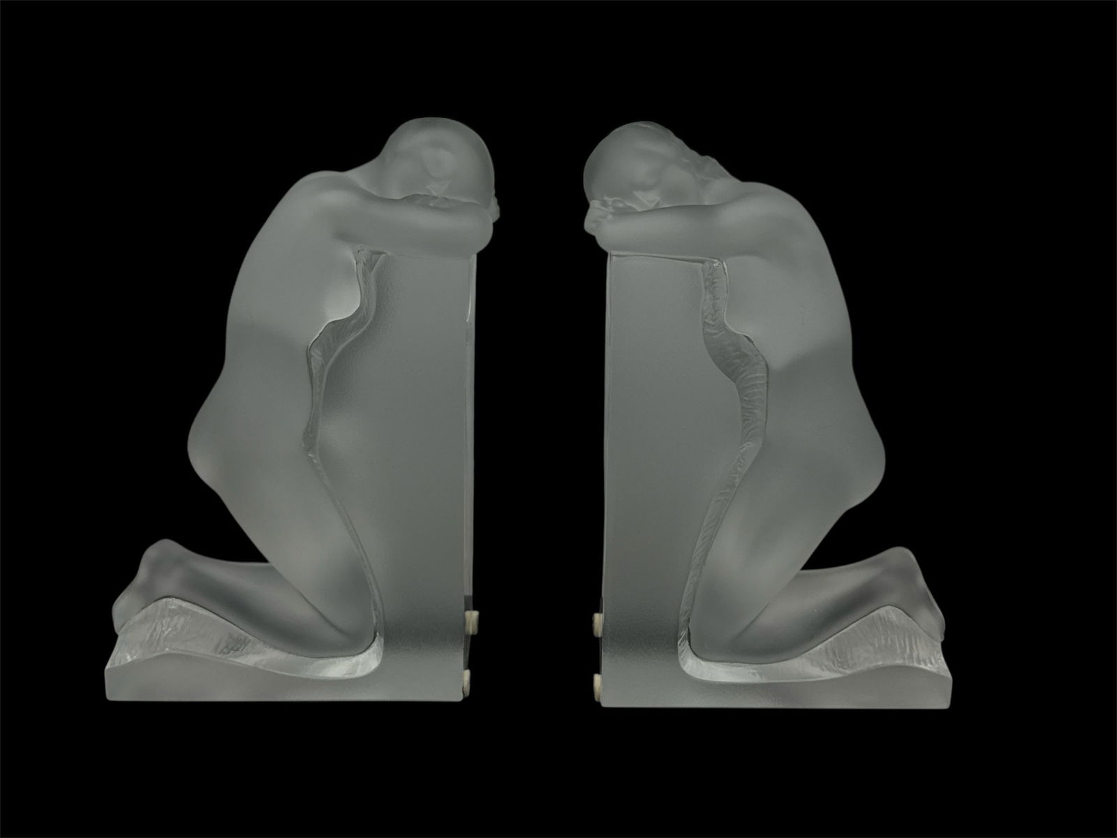 RARE Pair of Lalique Frosted Crystal Kneeling Female Figural Bookends: Striking pair of Lalique frosted crystal figural bookends depicting kneeling female forms in a contemplative pose. Each sculptural figure is rendered with graceful Art Deco lines, mounted on an integr