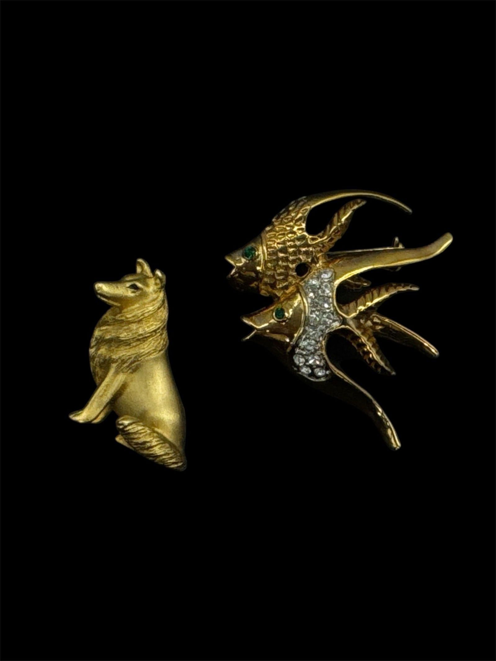 Pair of Gold Tone Animal Brooches (1-2in): Charming pair of vintage gold tone brooches including a stylized howling wolf head and a dynamic double-fish design. The fish brooch features textured detailing with clear rhinestone accents, while