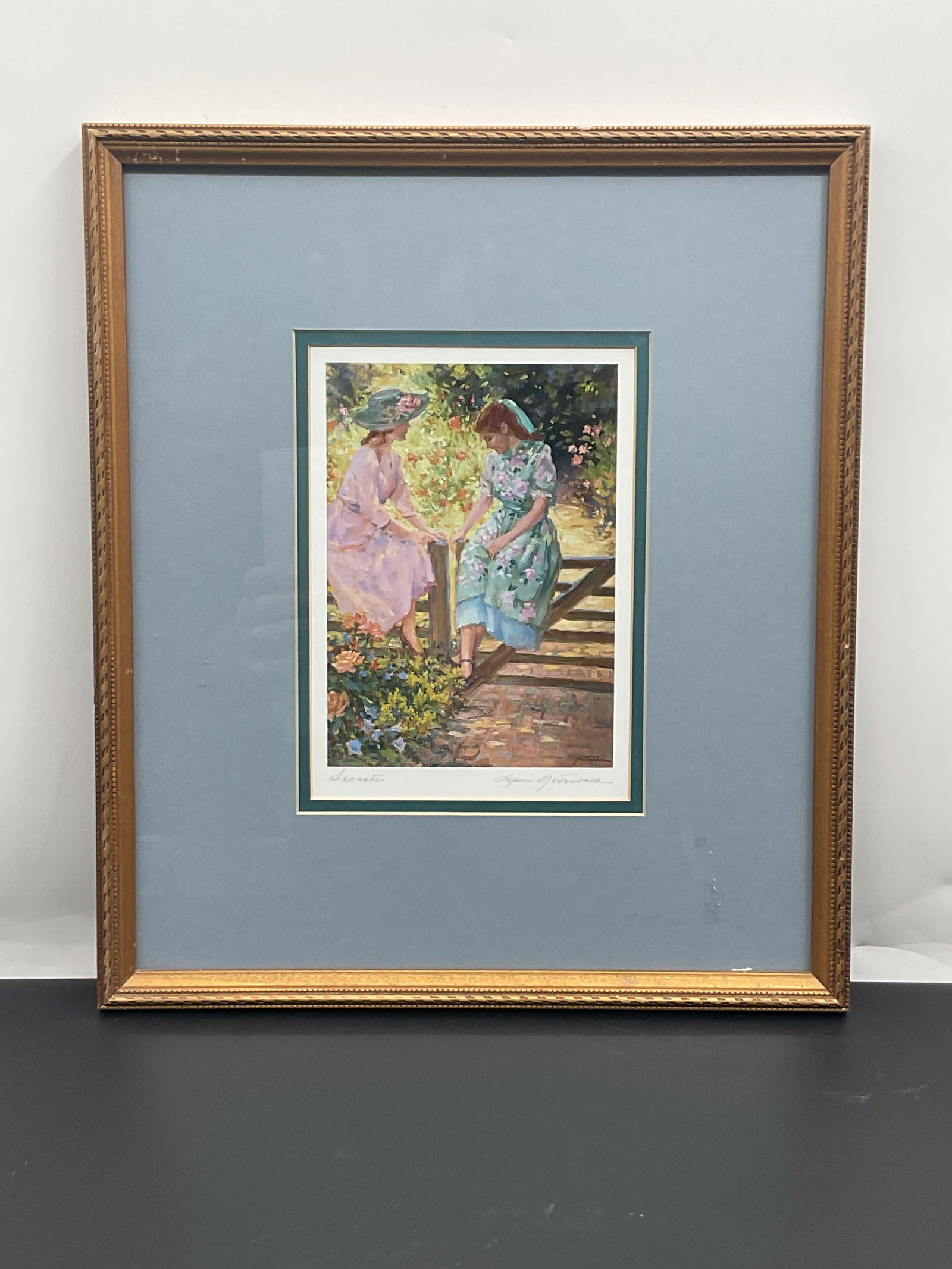 Lynn Gertenbach "Secrets" Print, Framed: Framed print of a painting titled "Secrets" by Lynn Gertenbach. The print depicts a woman in a garden setting. Lynn Gertenbach was a well known artist based in California, who has