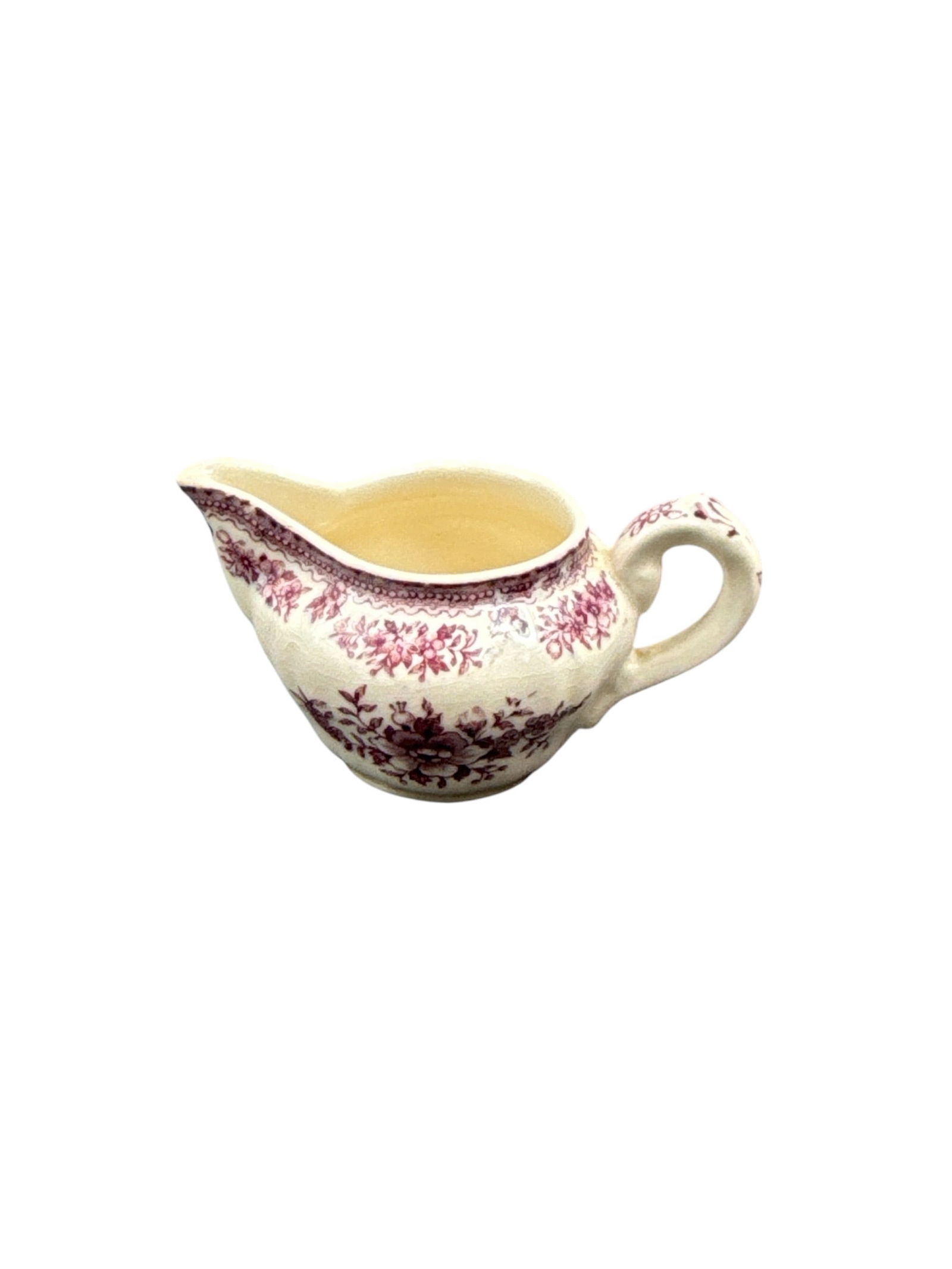 Wade England Ceramic Creamer with Pink Transferware Decoration: This lot features a ceramic creamer produced by Wade of England, decorated with a pink transferware floral and foliate pattern. The creamer has a classic rounded form with a shaped spout and applied