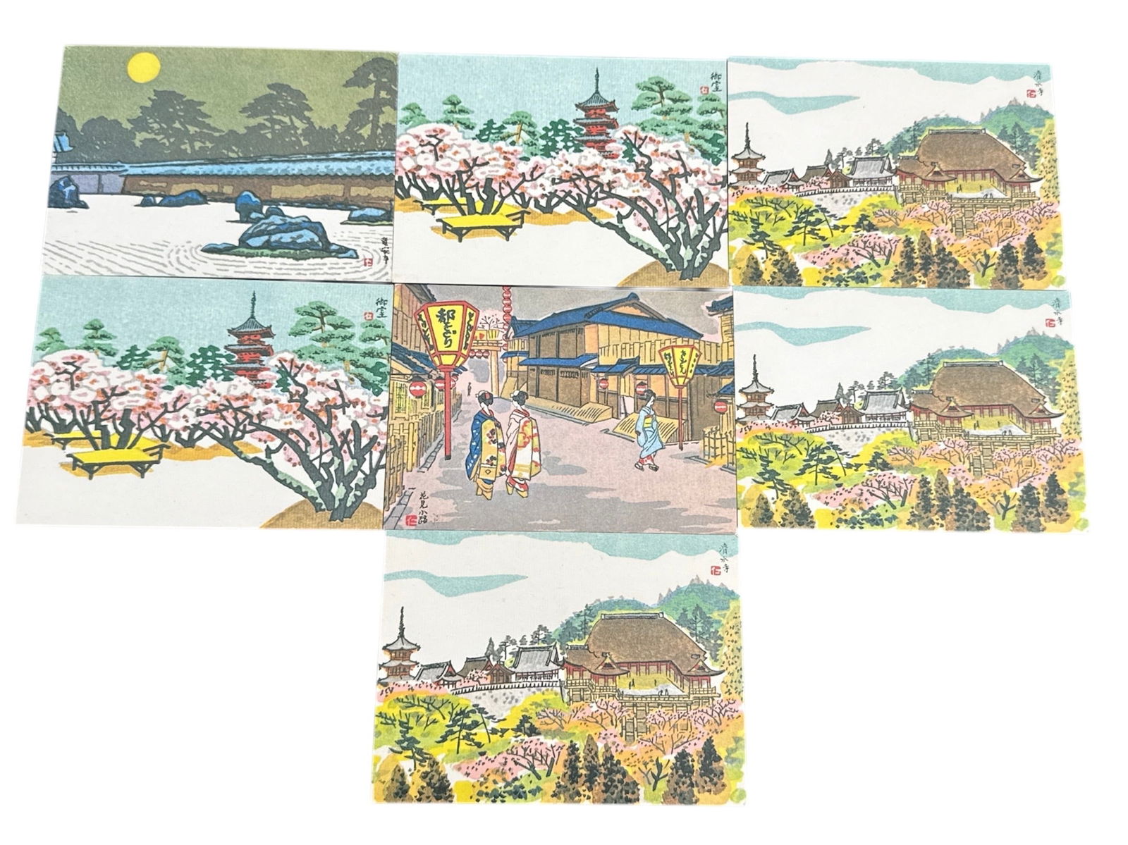 Group of Japanese Scenic Postcards with Temple and Landscape Views: This lot includes a group of Japanese scenic postcards depicting traditional landscapes, temples, gardens, and architectural views. The images are rendered in a colorful illustrative style,