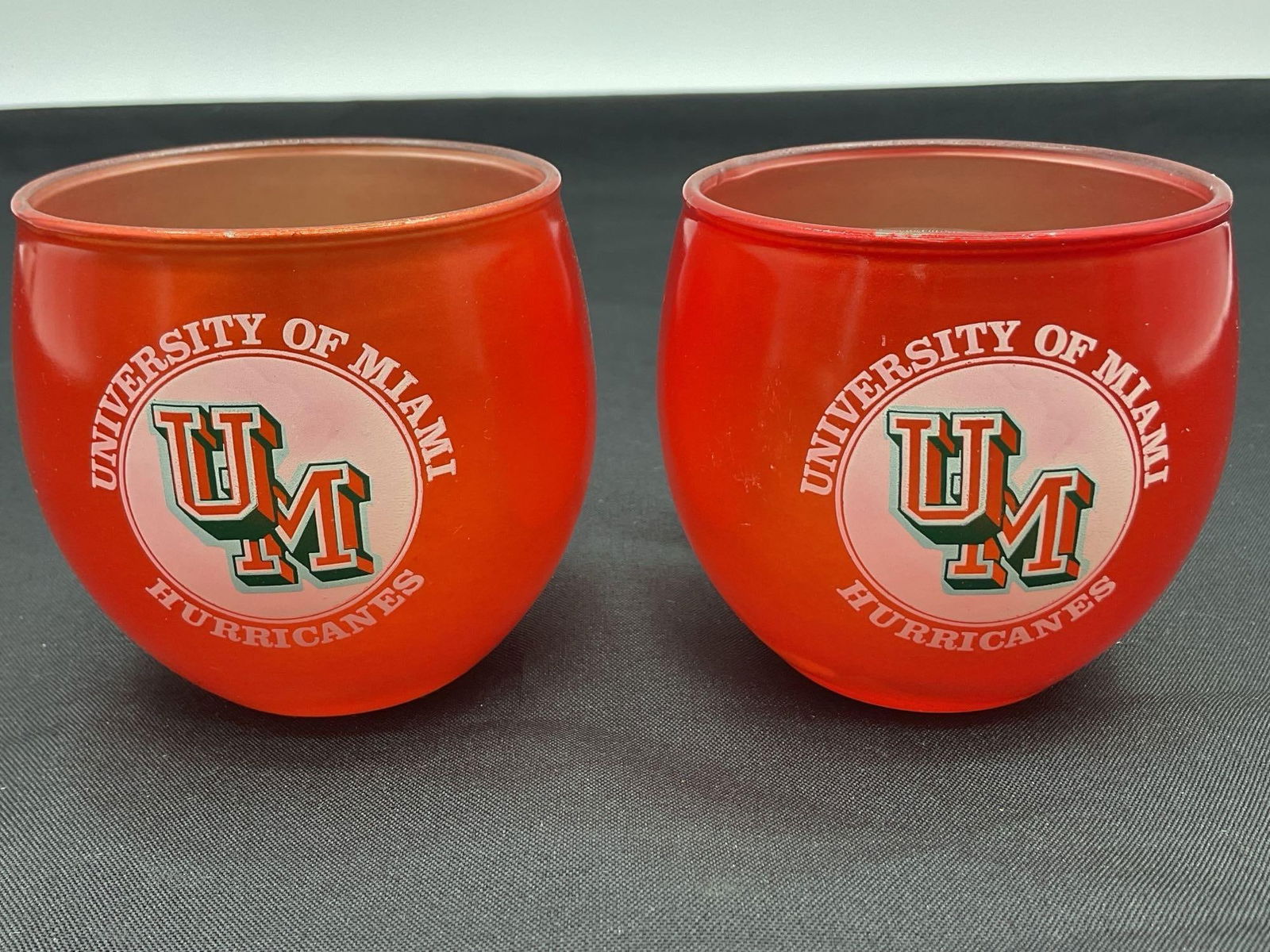 University of Miami Hurricanes Glass Candle Holders (Set of 2): This set of two University of Miami Hurricanes-themed glass candle holders features the classic "U of M" logo on an orange exterior. Designed to hold small votive or tea light candles,