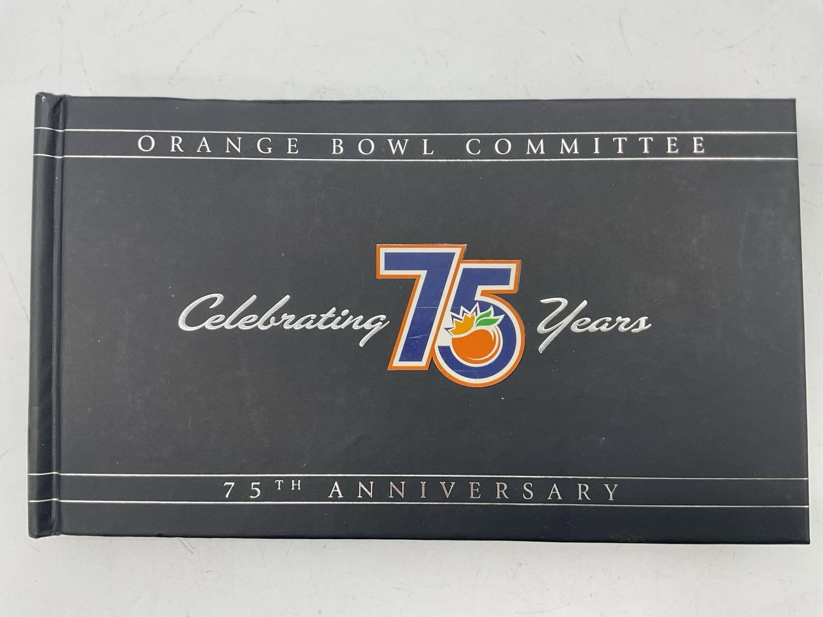 Orange Bowl Committee 75th Anniversary Book: Commemorative hardcover book celebrating the 75-year history of the Orange Bowl, featuring historical moments, iconic games, and legendary players. Dimensions: L9.5in W6in Medium: Hardcover book with