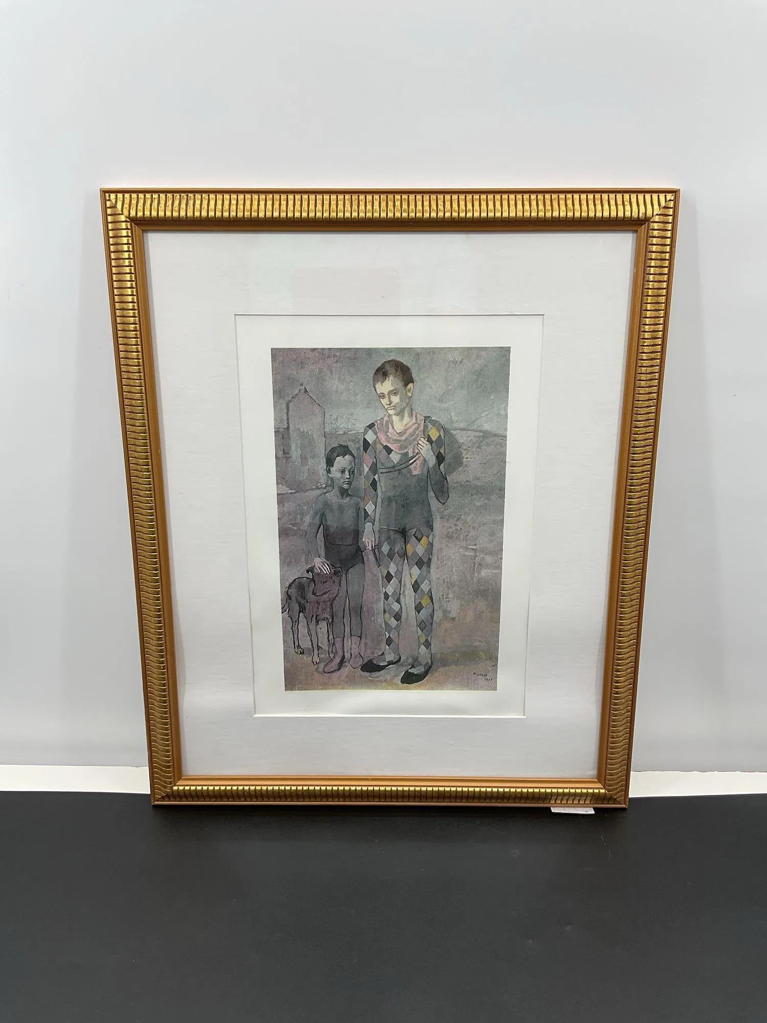 Les Saltimbanques after Pablo Picasso (Spain, 1881-1973) Lithograph: A framed reproduction of Acrobat and Young Harlequin, an iconic painting originally created by Pablo Picasso in 1905 during his Rose Period. The artwork depicts two solemn figures, likely performers,
