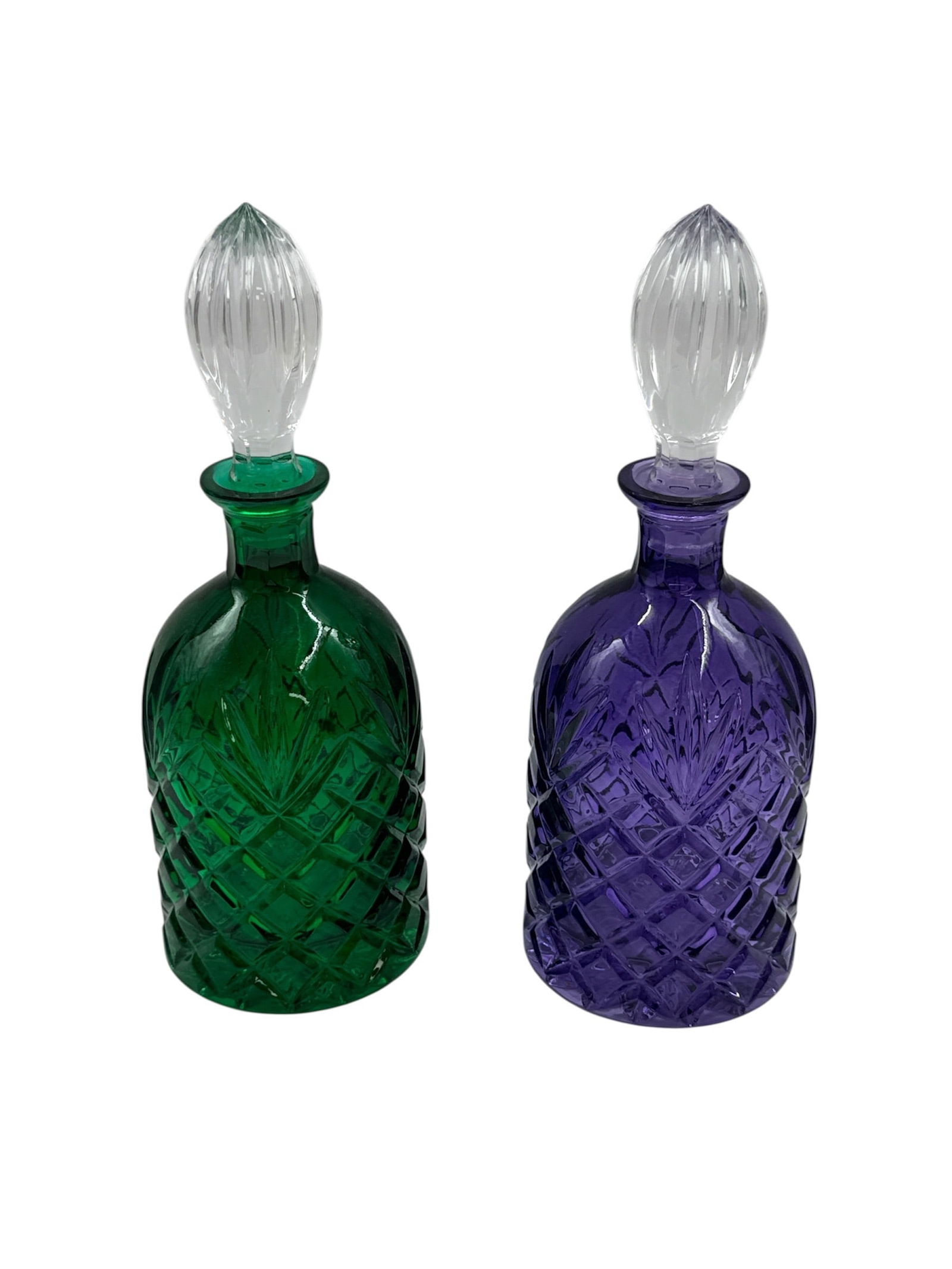 Pair of Colored Cut Glass Decanters with Stoppers Green and Purple: Striking pair of colored cut glass decanters, one emerald green and one deep amethyst purple, each featuring an allover diamond lattice pattern. The rounded bodies taper to short necks and are fitted